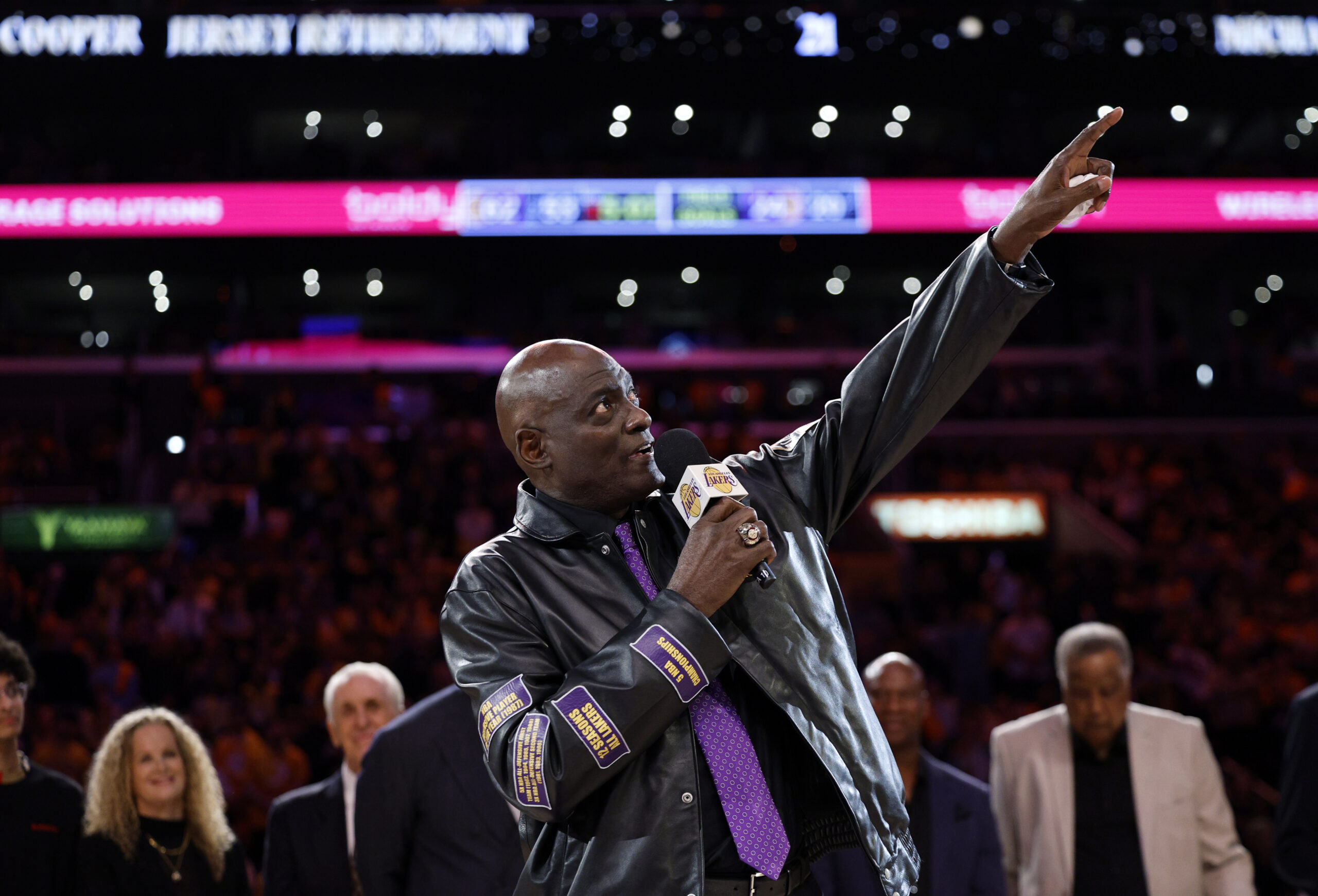 Former Lakers star Michael Cooper, center, gestures toward the rafters...