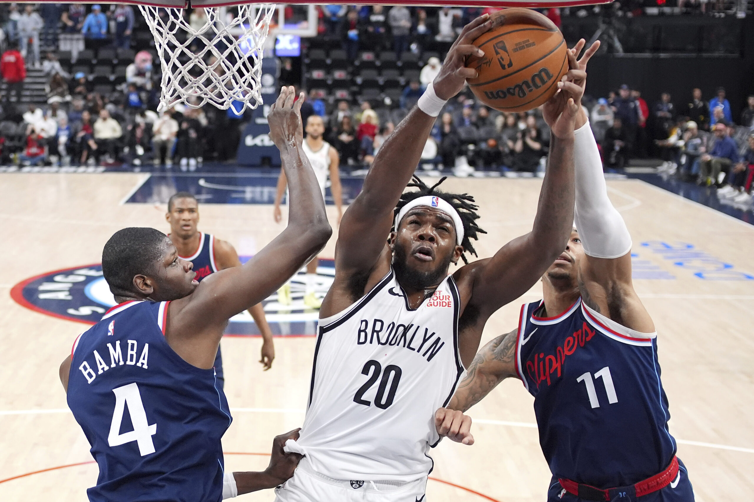 Brooklyn Nets center Day’Ron Sharpe, center, grabs a rebound away...