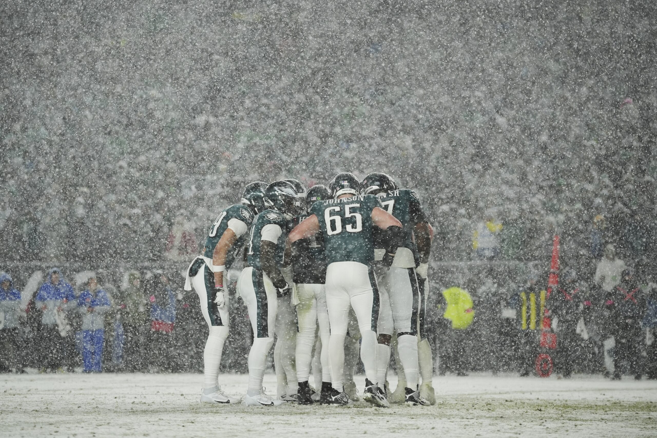 Philadelphia Eagles players huddle as it snows during the second...