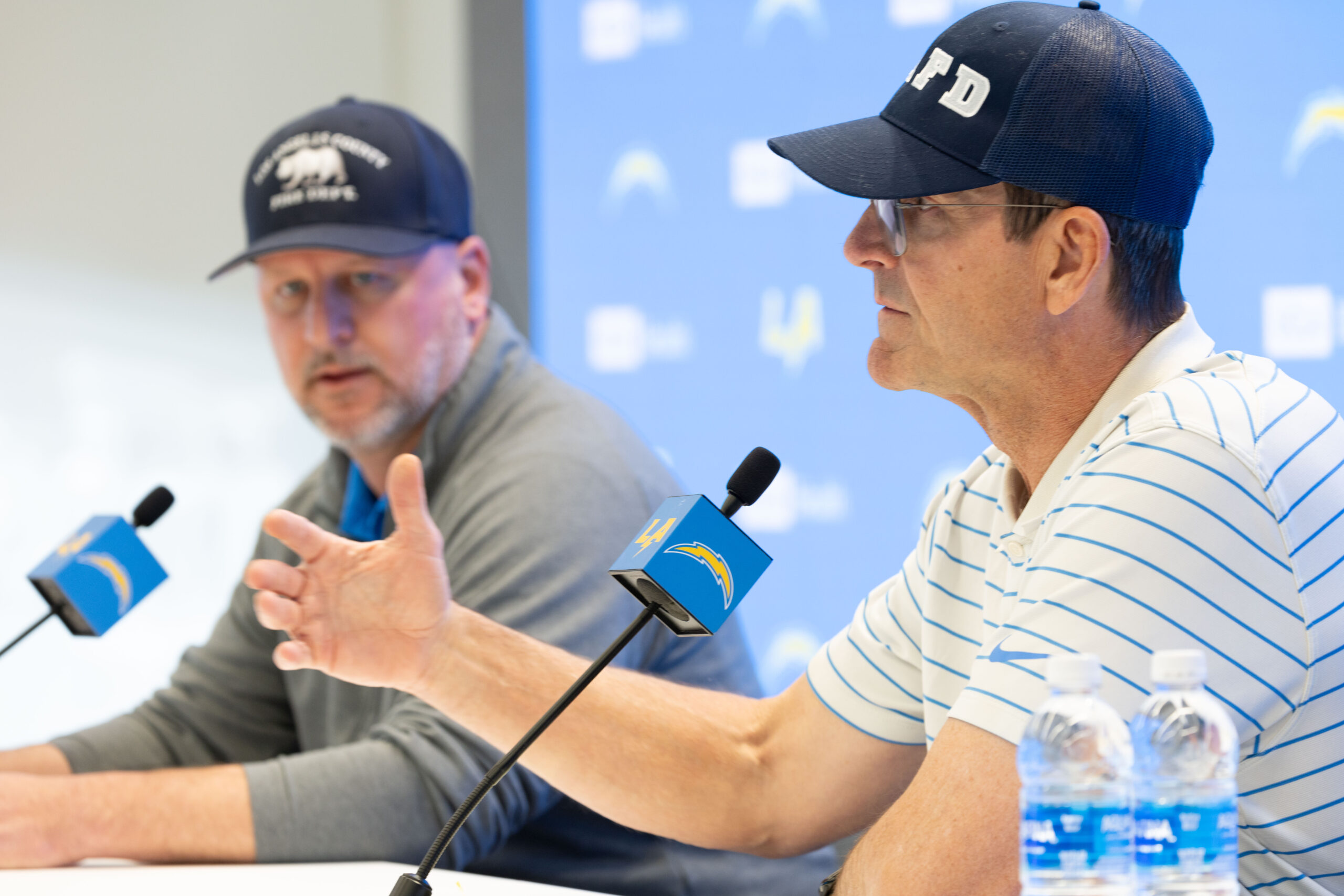 Chargers head coach Jim Harbaugh, right, speaks to reporters as...