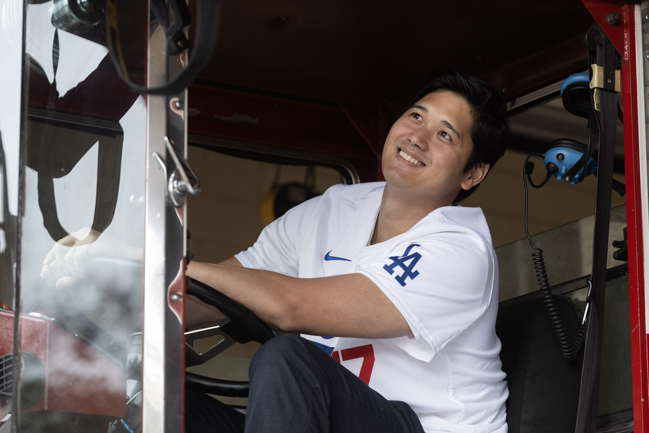 Dodgers star Shohei Ohtani smiles from inside a tiller truck...