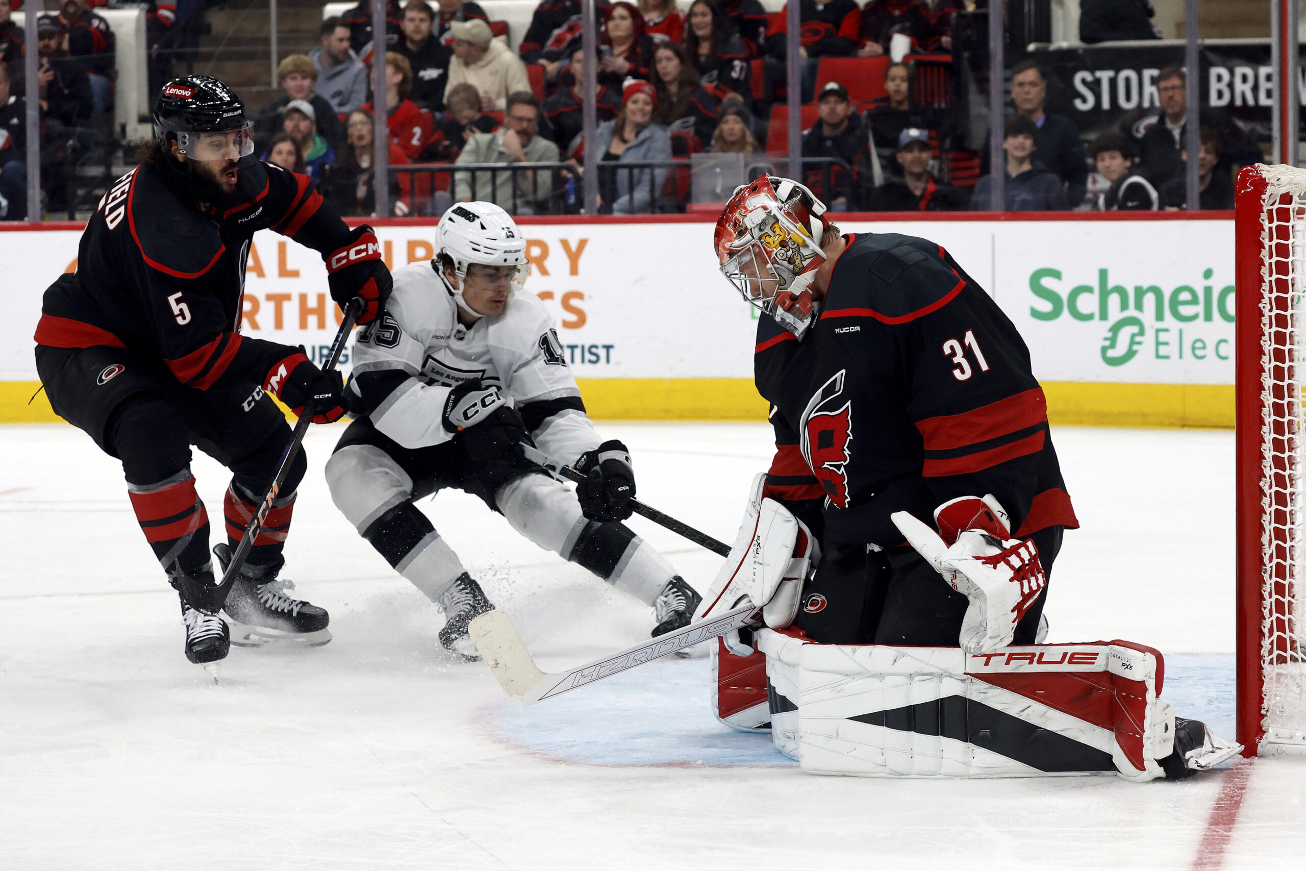 Kings’ Alex Turcotte (15) shoots the puck between Carolina Hurricanes’...