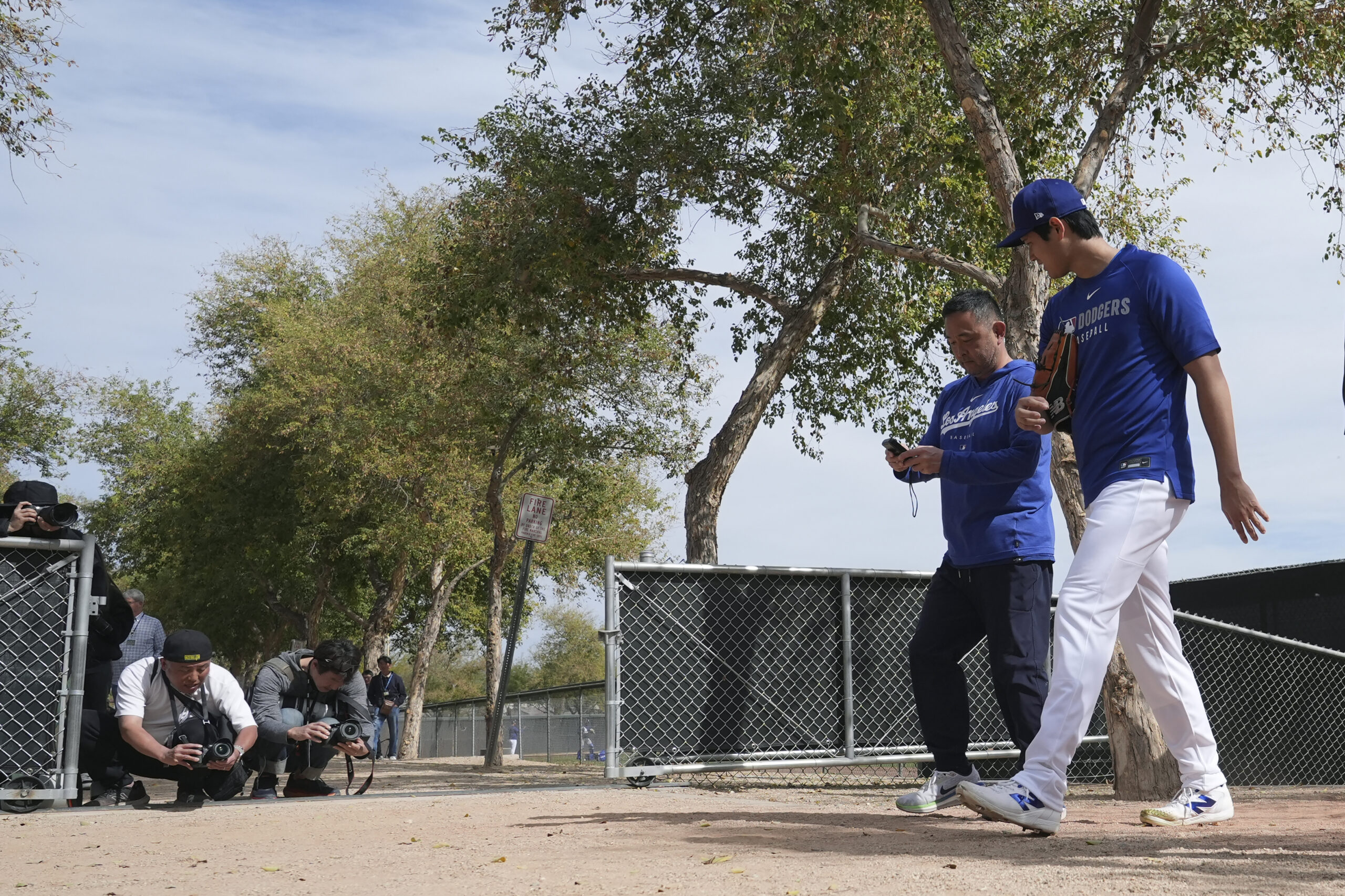 Dodgers star Shohei Ohtani, right, walks back to the clubhouse...