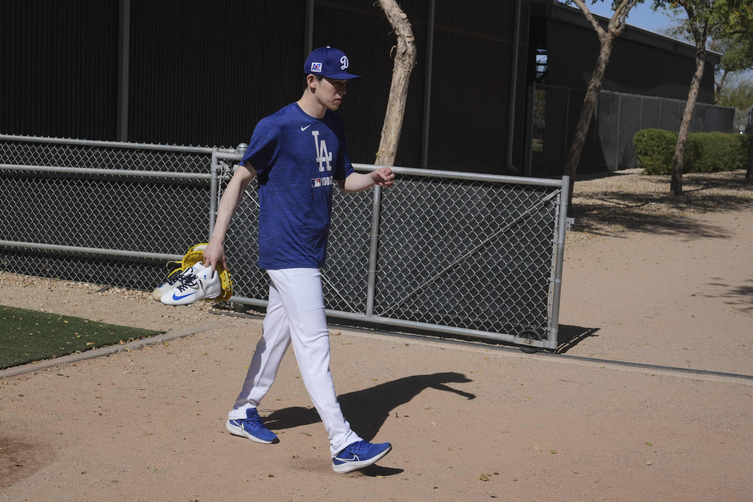 Dodgers pitcher Roki Sasaki walks to a practice field to...