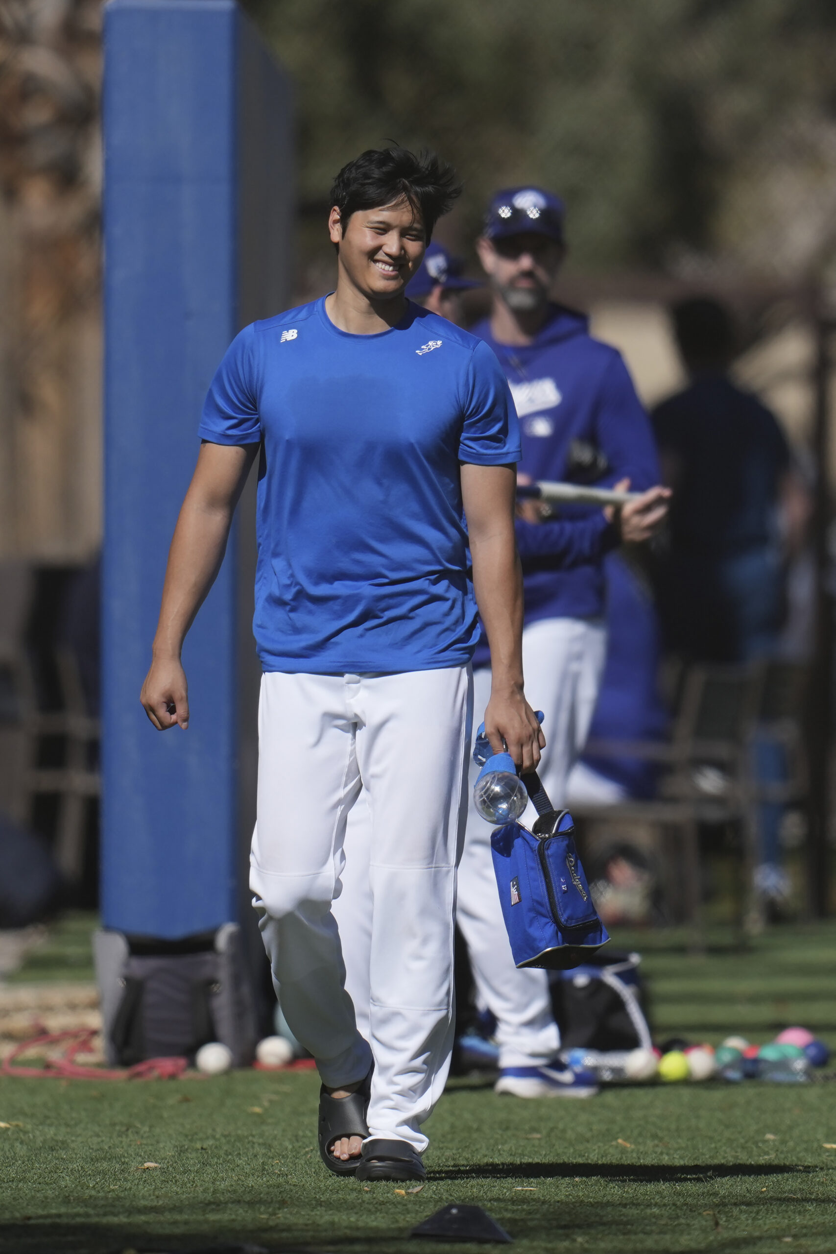 Dodgers star Shohei Ohtani smiles as he walks past teammates...