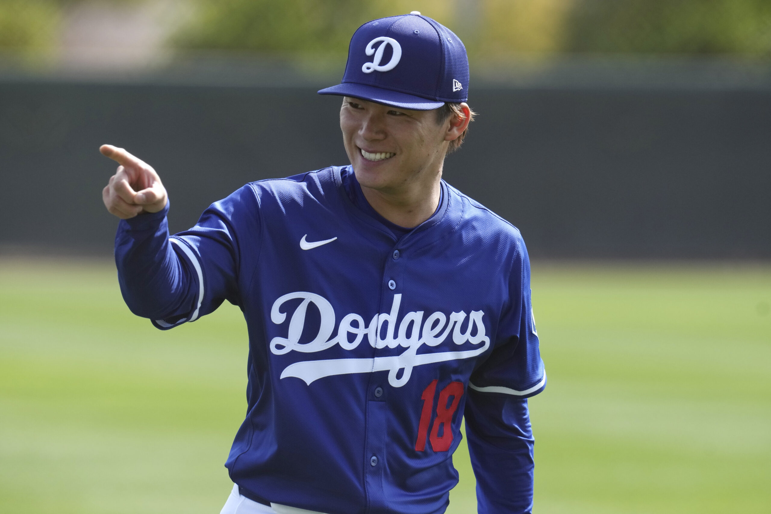 Dodgers pitcher Yoshinobu Yamamoto smiles as he warms up on...