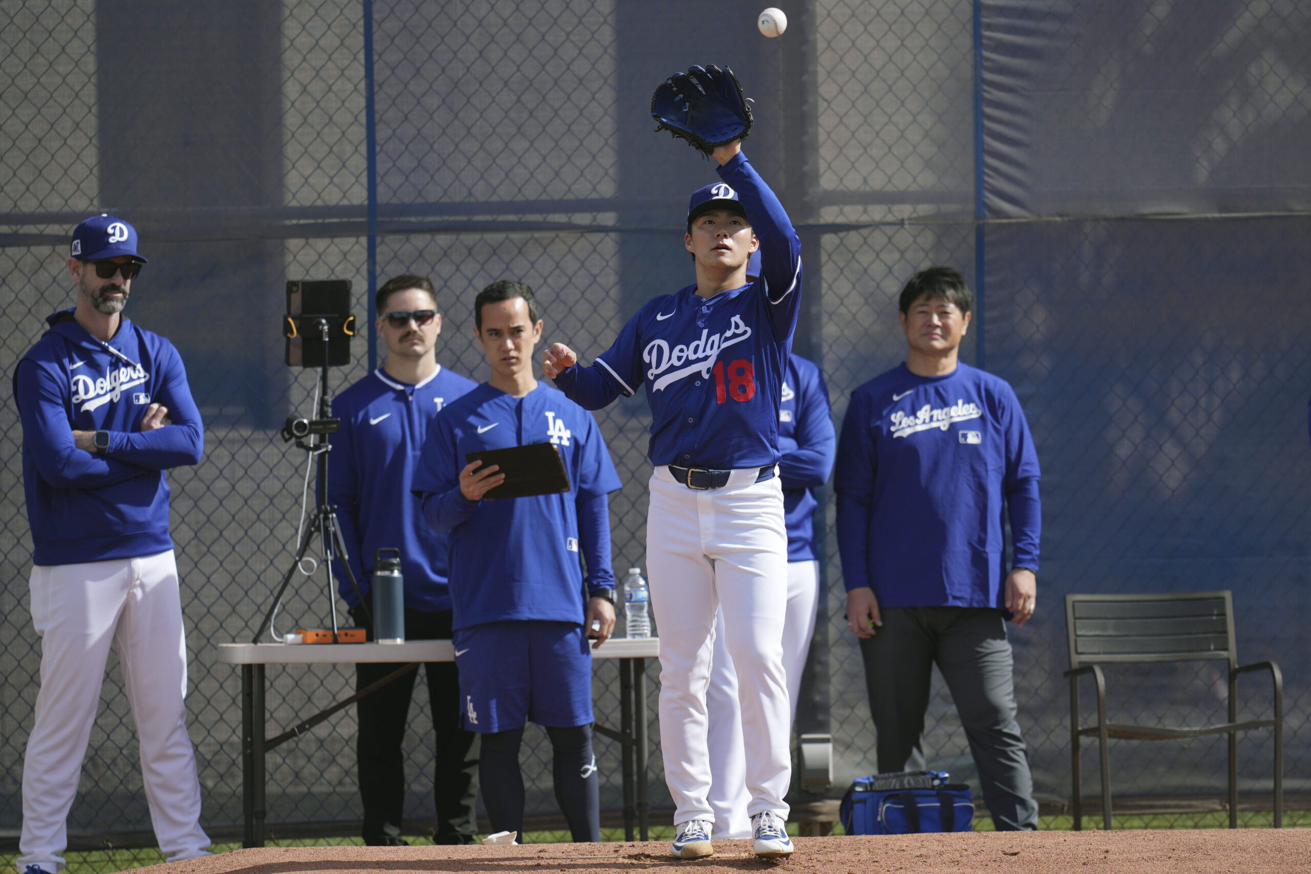 Dodgers pitcher Yoshinobu Yamamoto reaches for a ball during a...