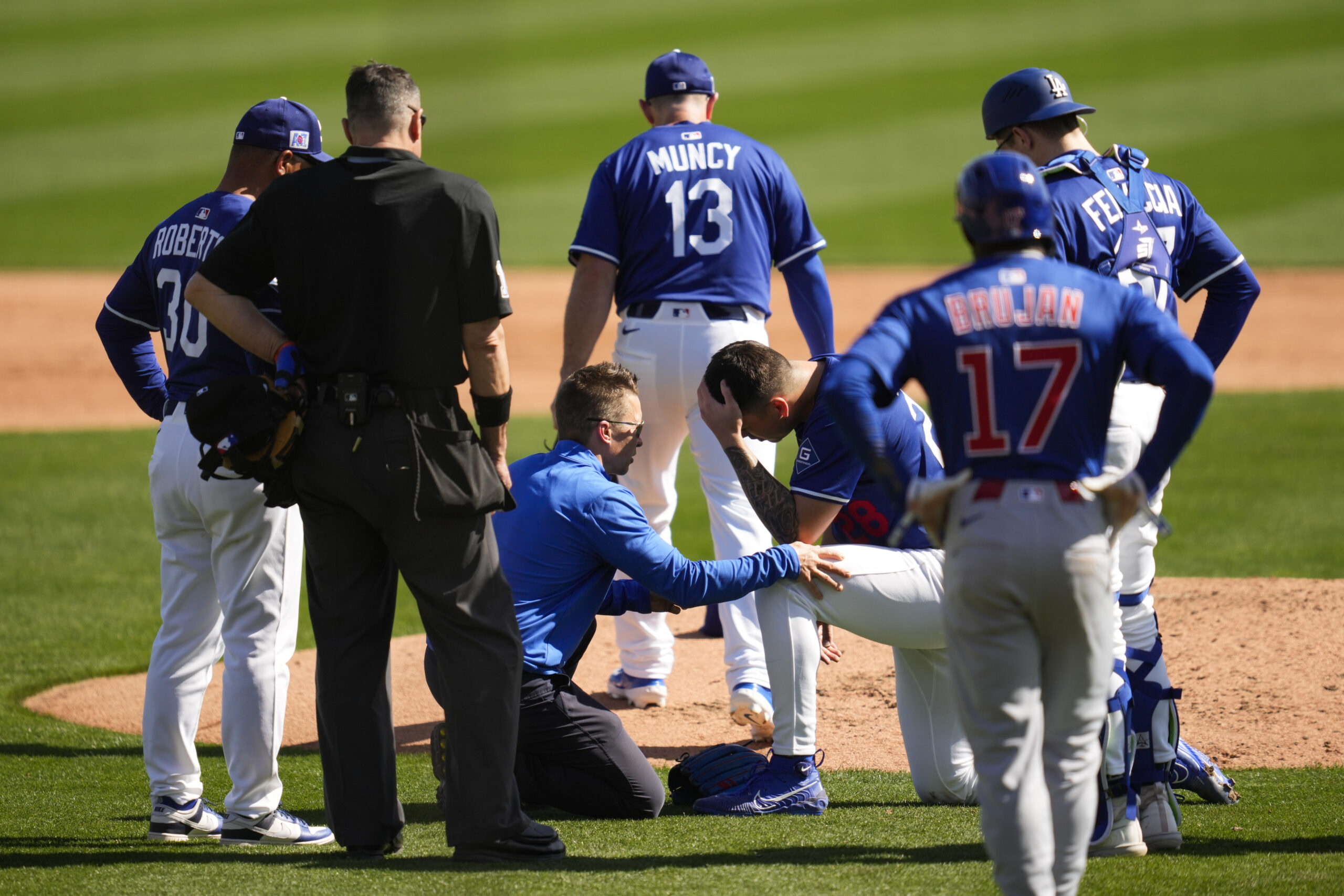 Dodgers pitcher Bobby Miller is looked at by a trainer...