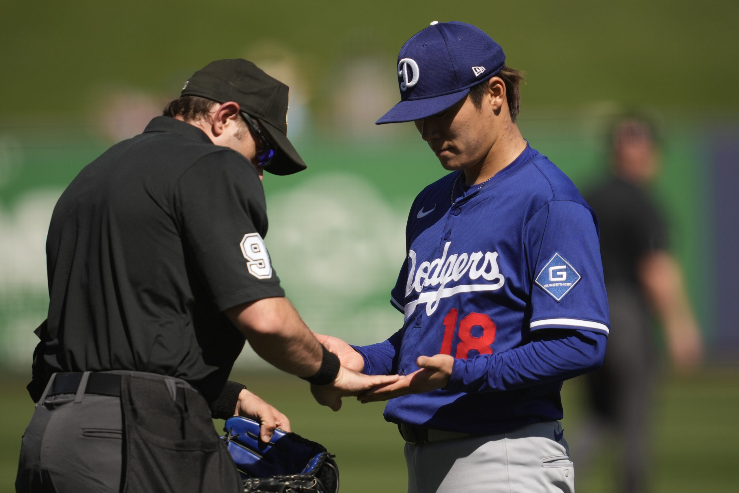 Dodgers starting pitcher Yoshinobu Yamamoto is inspected by umpire Alex...