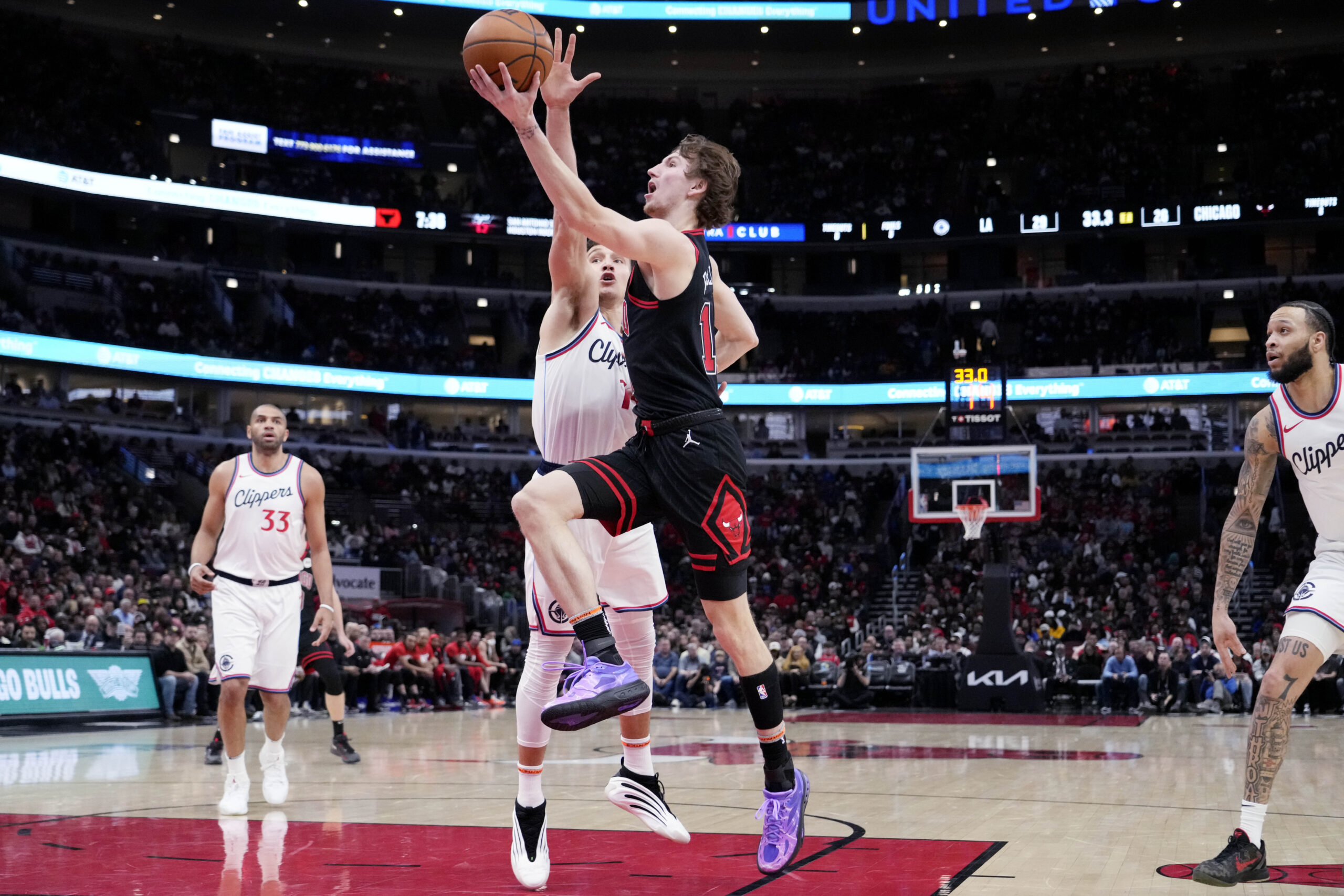 Chicago Bulls forward Matas Buzelis, right, drives to the basket...