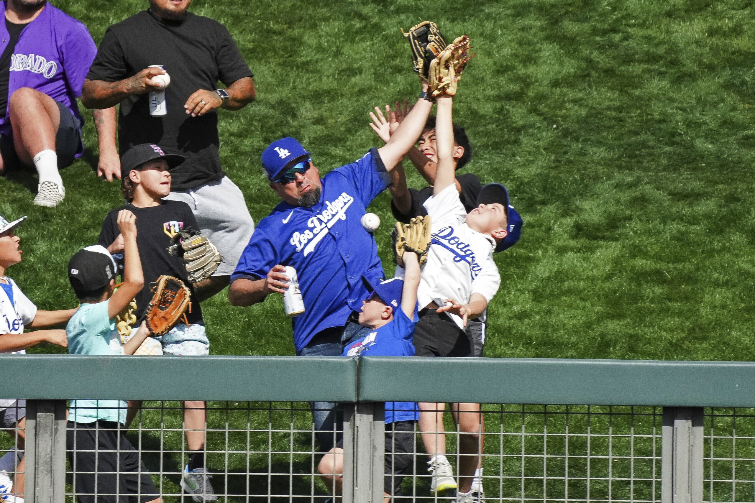 Baseball fans vie for a baseball thrown to them by...