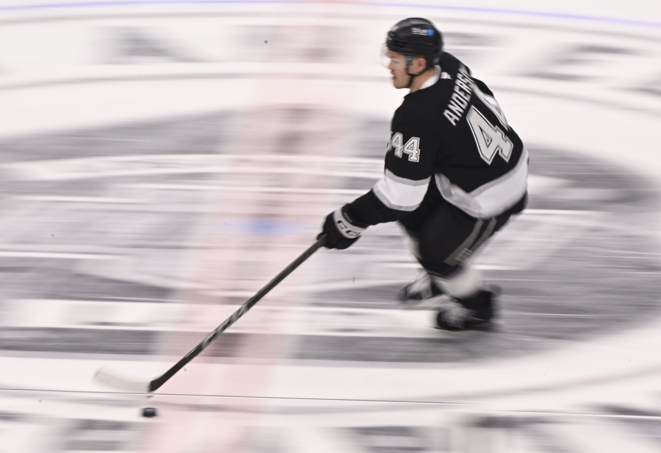 Mikey Anderson #44 of the Kings controls the puck against...