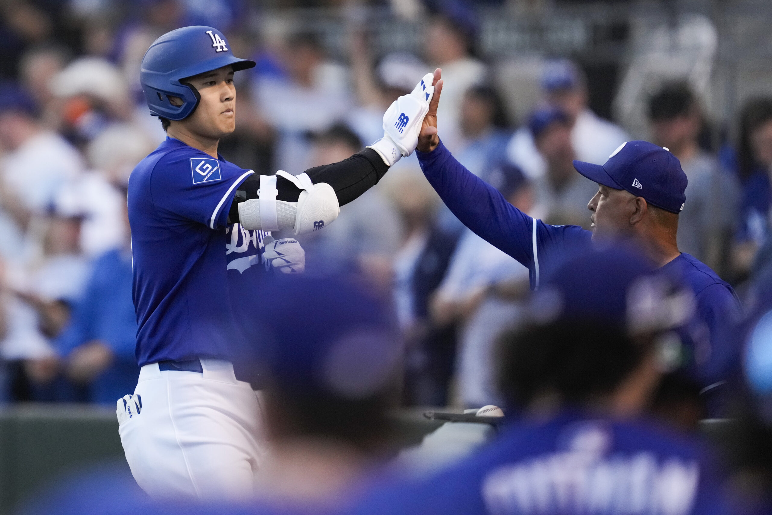 Dodgers designated hitter Shohei Ohtani high-fives manager Dave Roberts after...