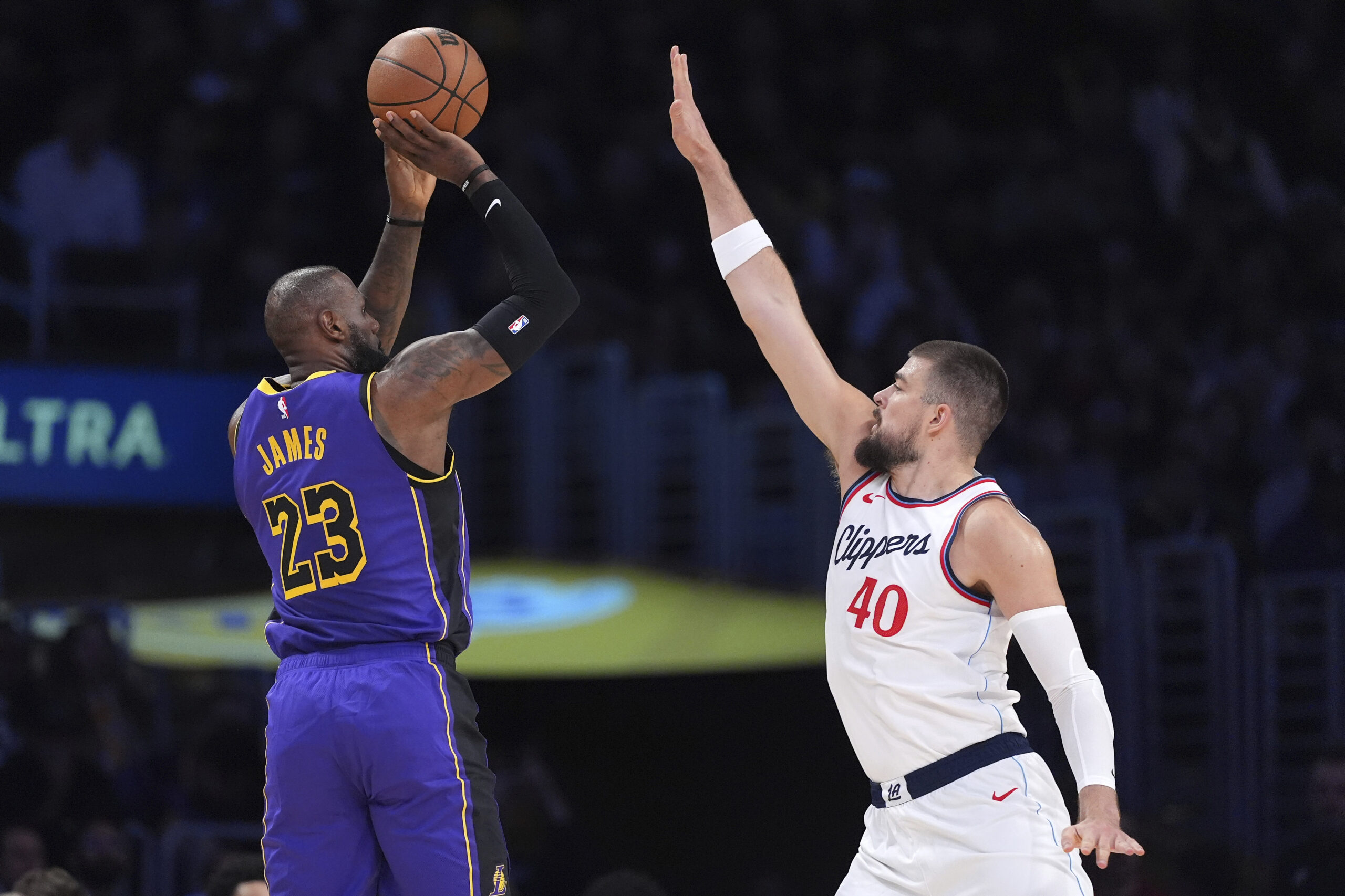 Lakers forward LeBron James, left, shoots as Clippers center Ivica...