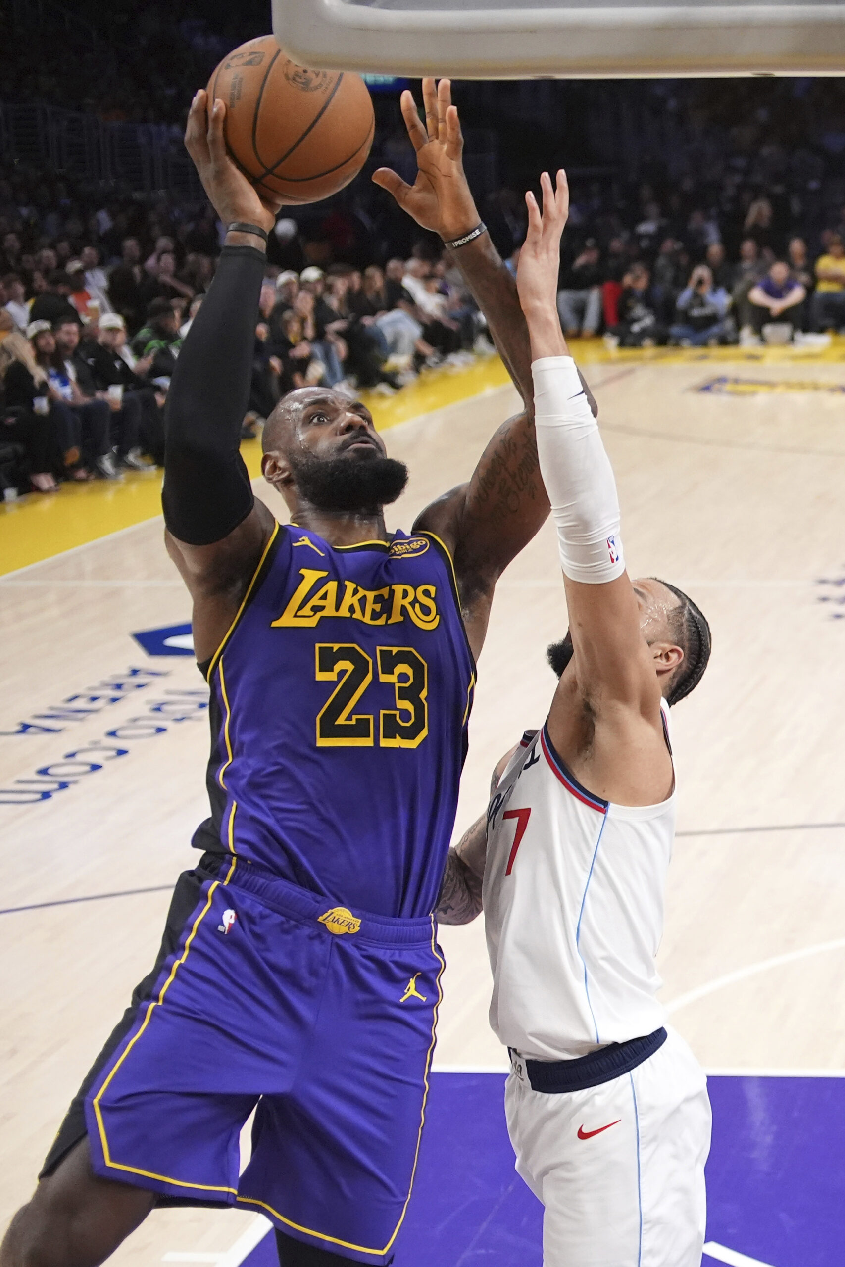 Lakers forward LeBron James, left, shoots as Clippers guard Amir...