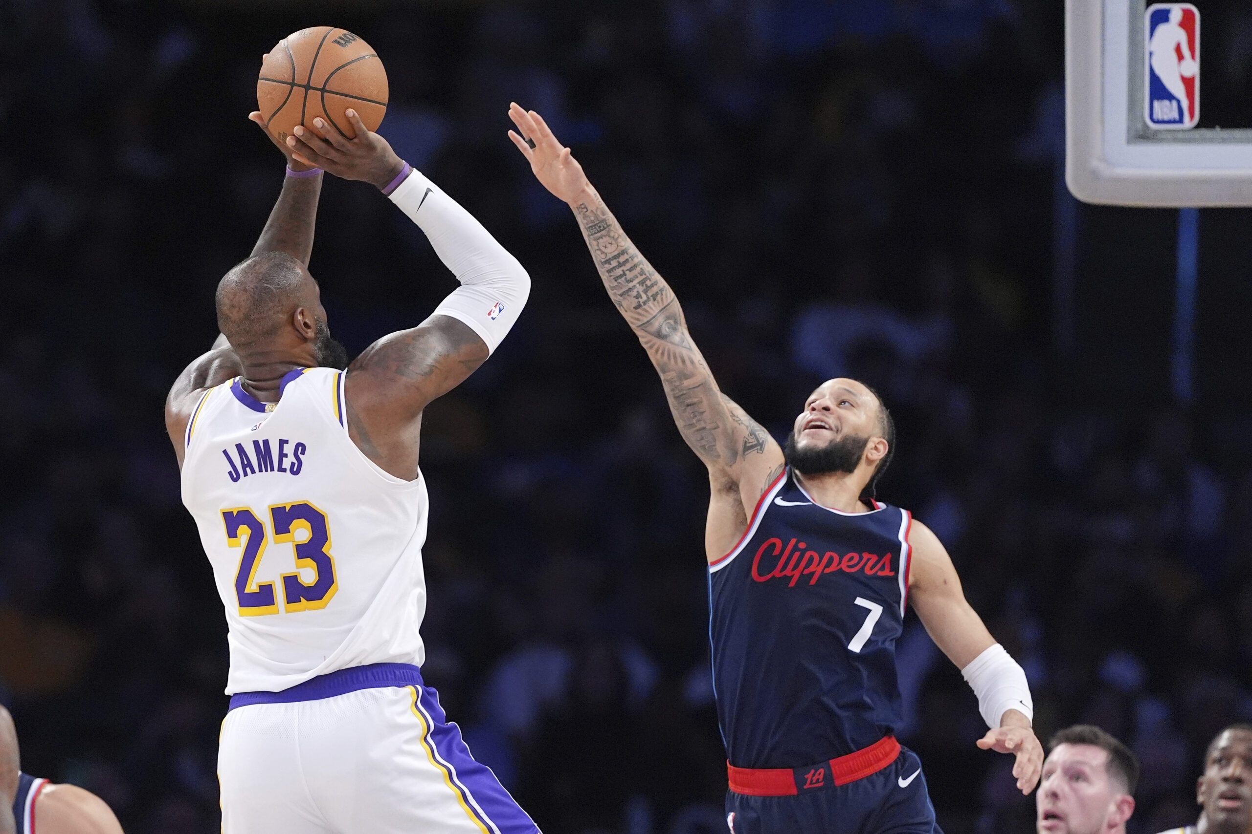 Lakers forward LeBron James, left, shoots as Clippers guard Amir...