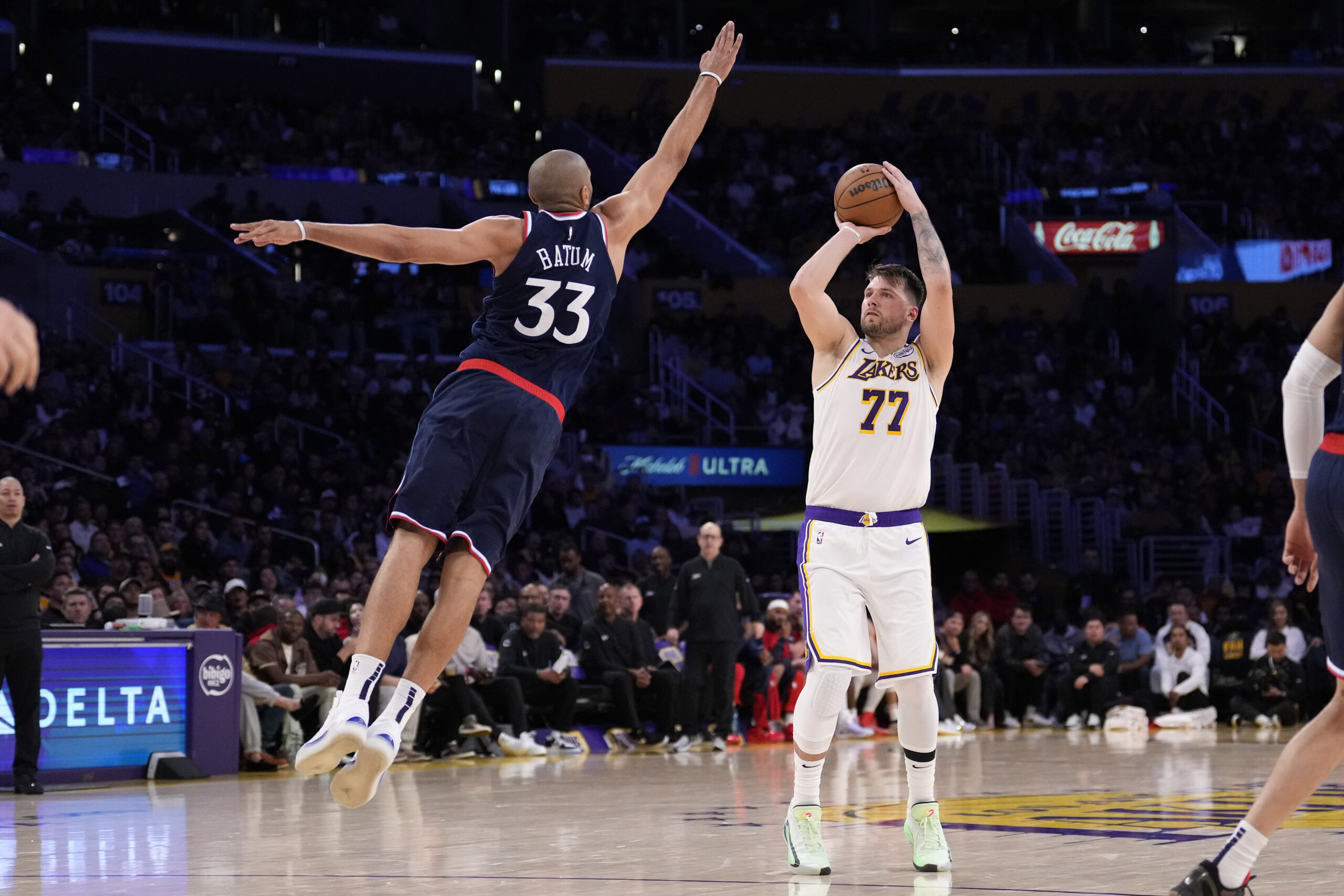 Lakers guard Luka Doncic, right, shoots as Clippers forward Nicolas...