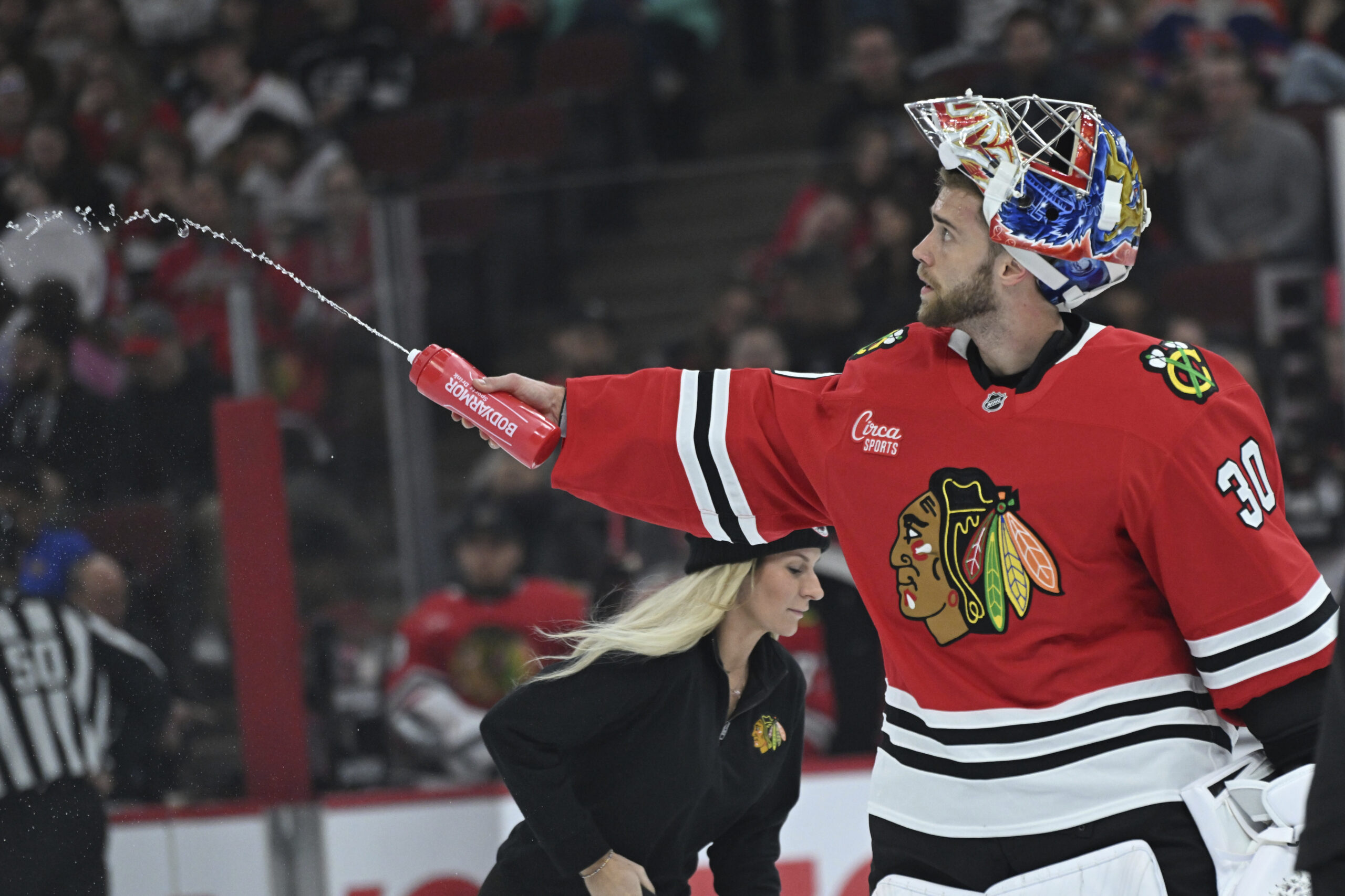 Chicago Blackhawks goalie Spencer Knight sprays water before a game...