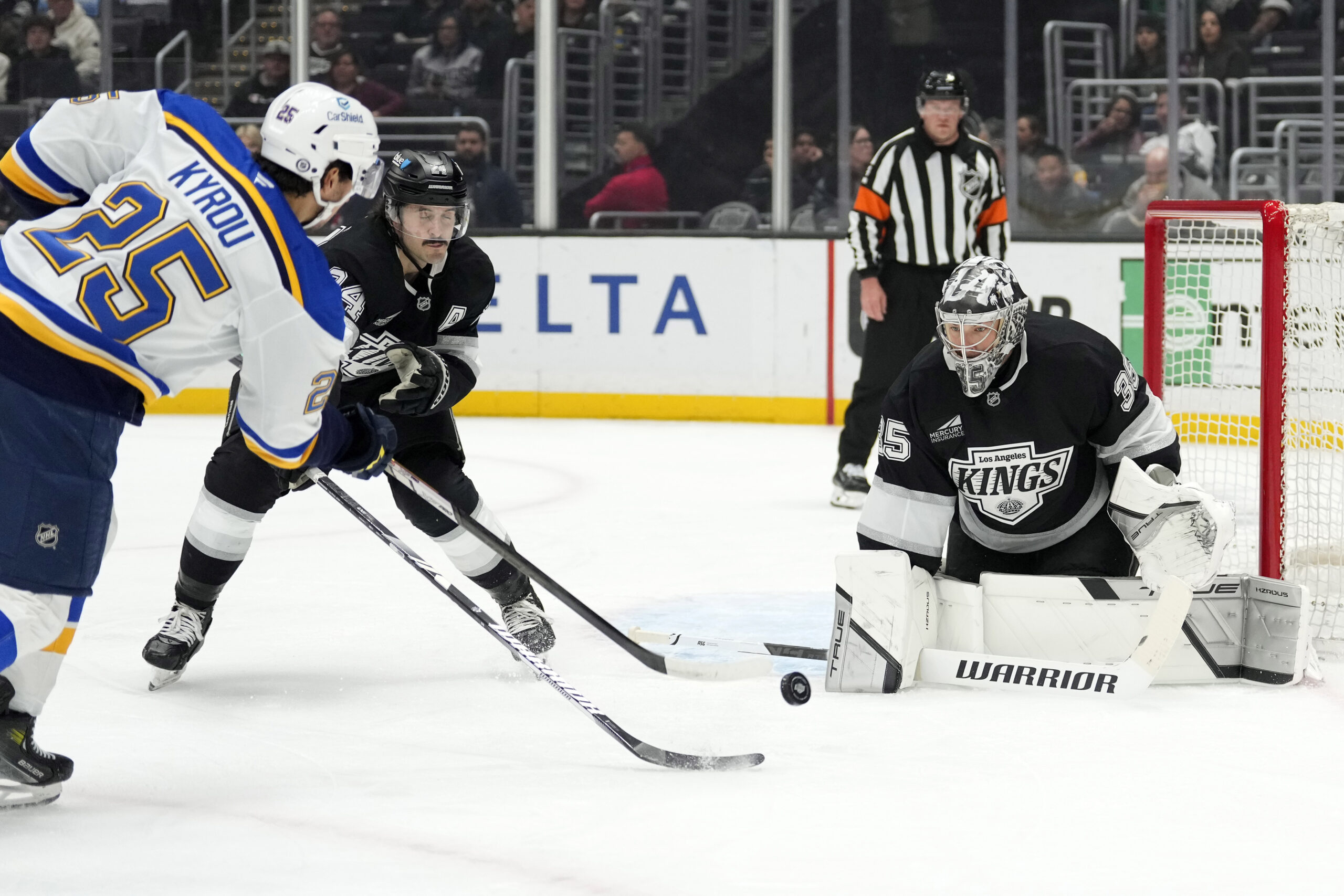 St. Louis Blues center Jordan Kyrou, left, shoots the puck...