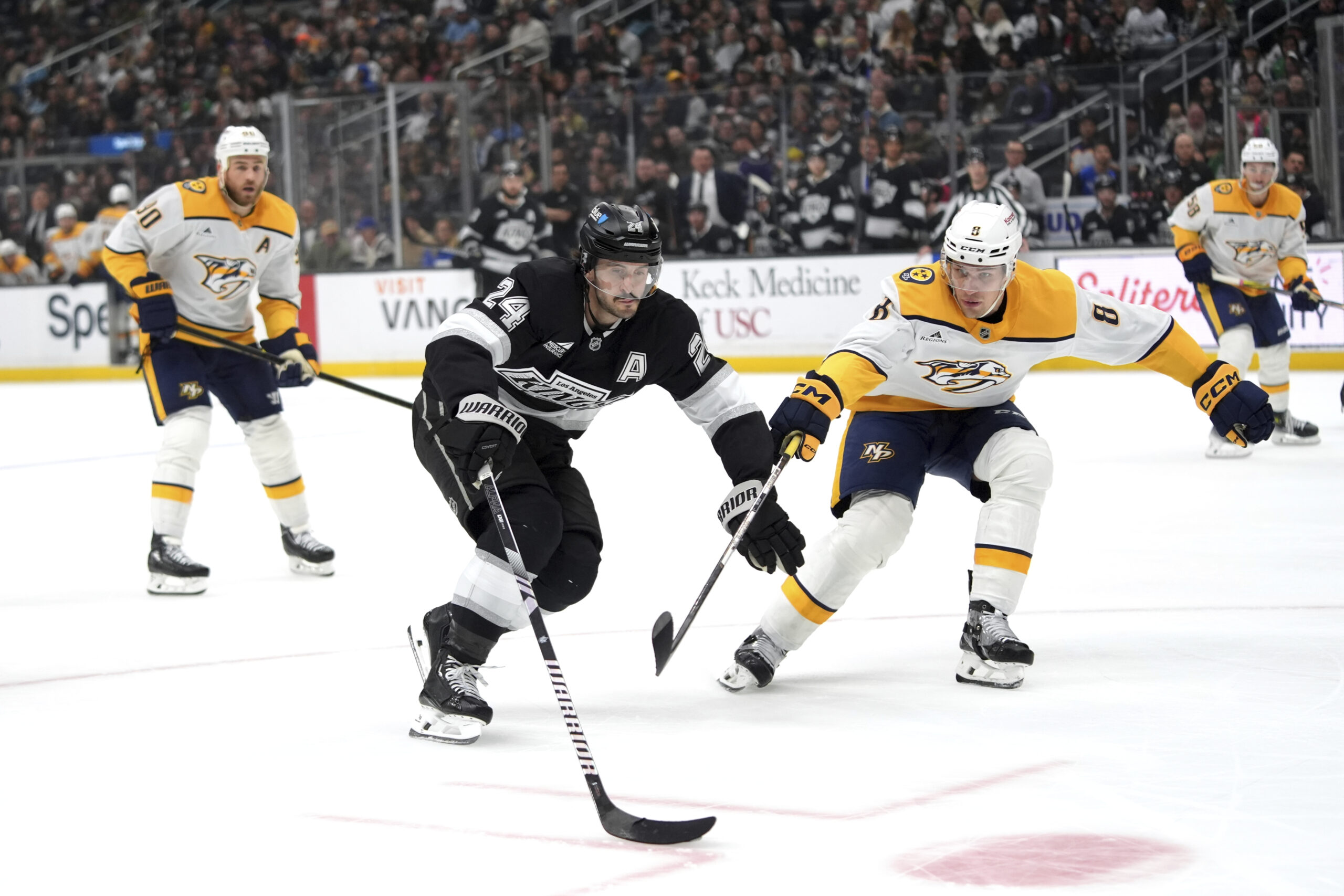 Kings center Phillip Danault (24) moves the puck under pressure...