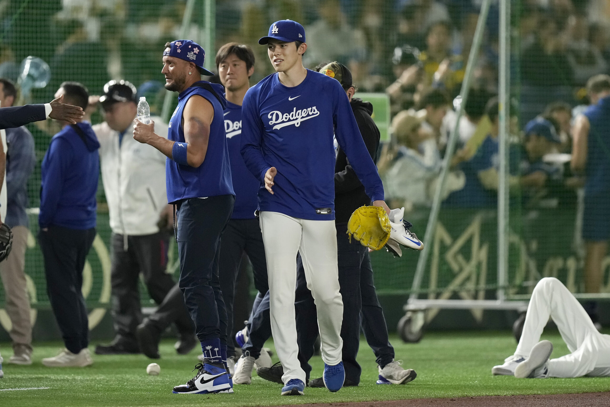 Dodgers pitcher Roki Sasaki, middle, walks on the field before...