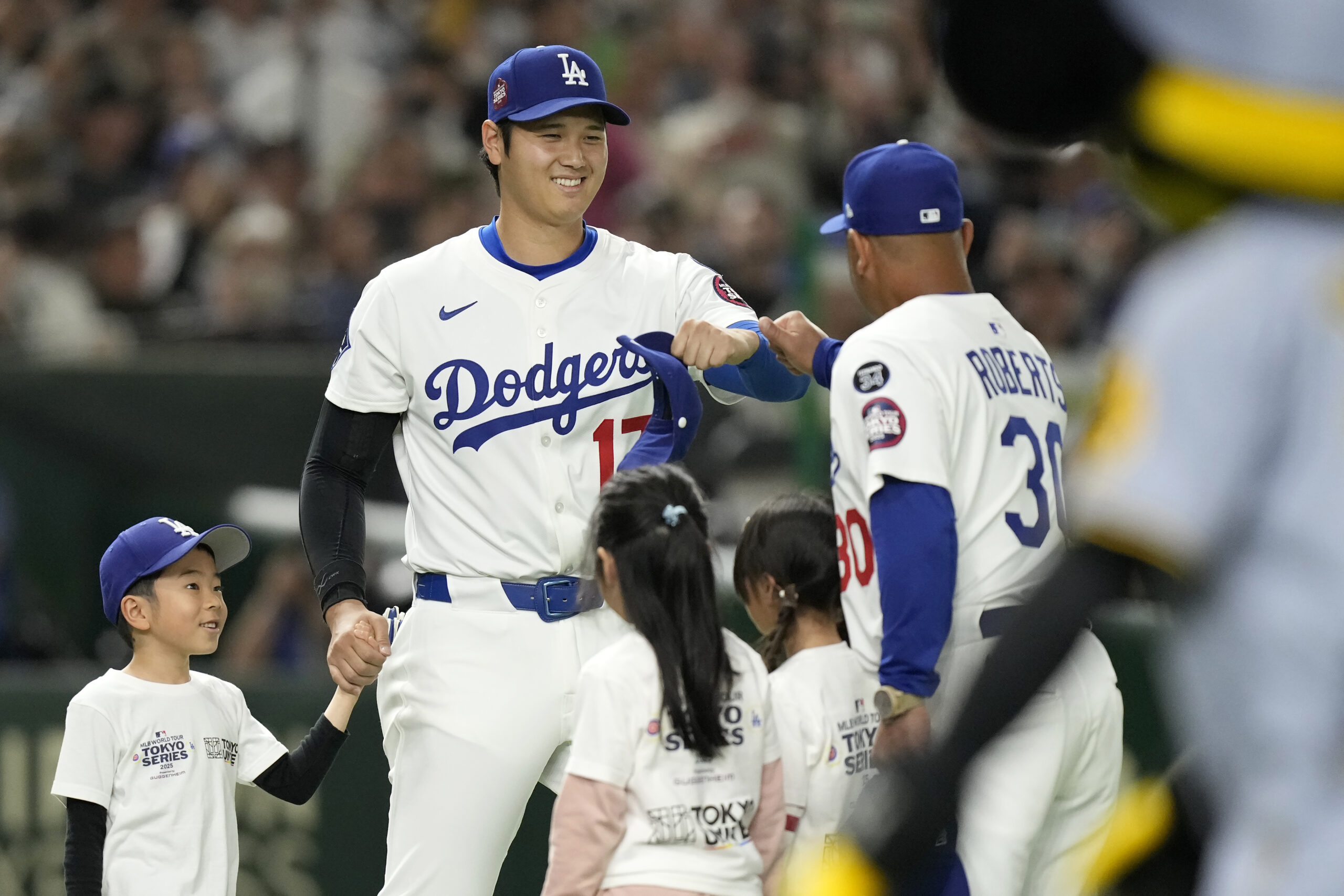 Dodgers star Shohei Ohtani, middle left, greets Manager Dave Roberts...