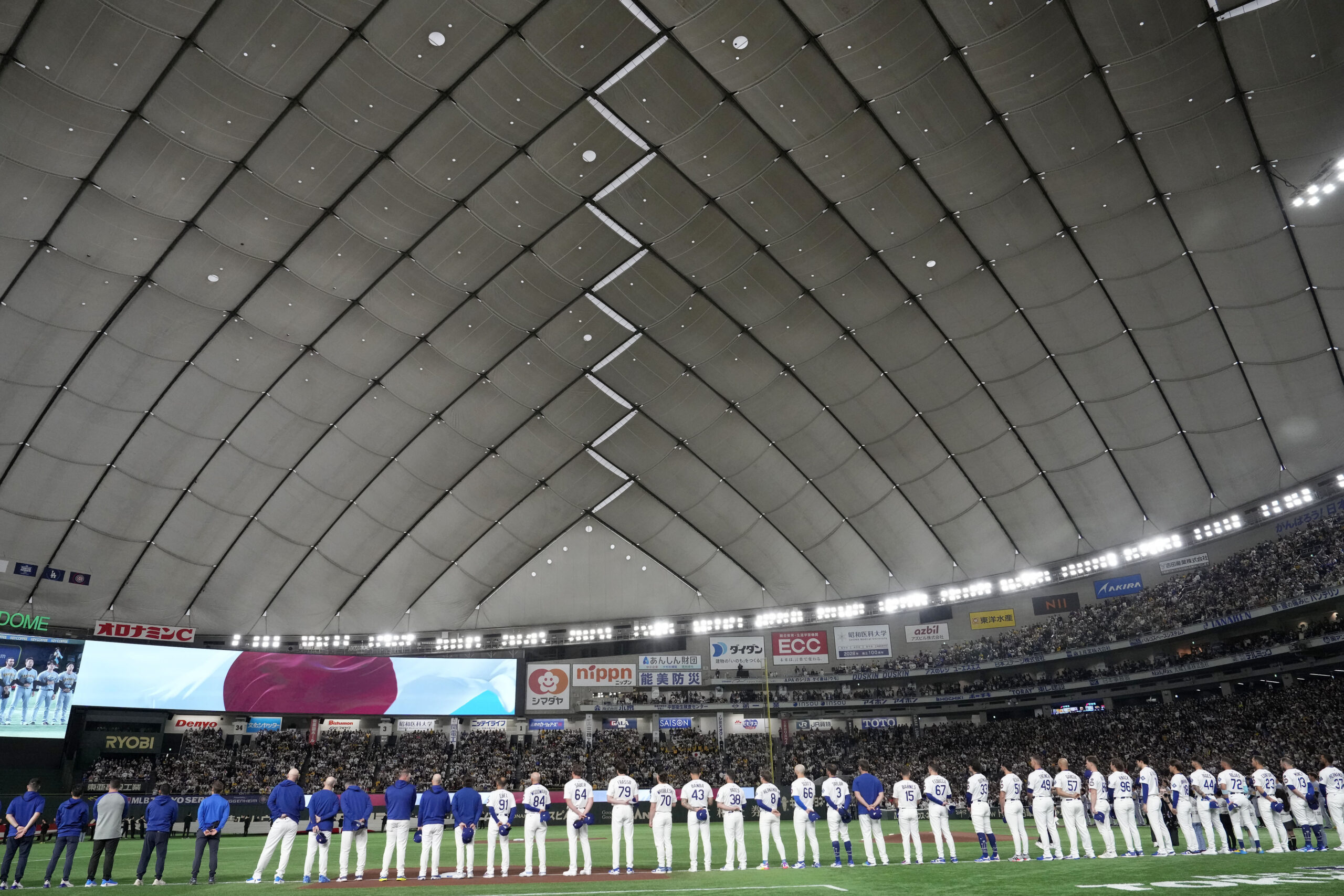 Dodgers players stand during the national anthem of Japan before...