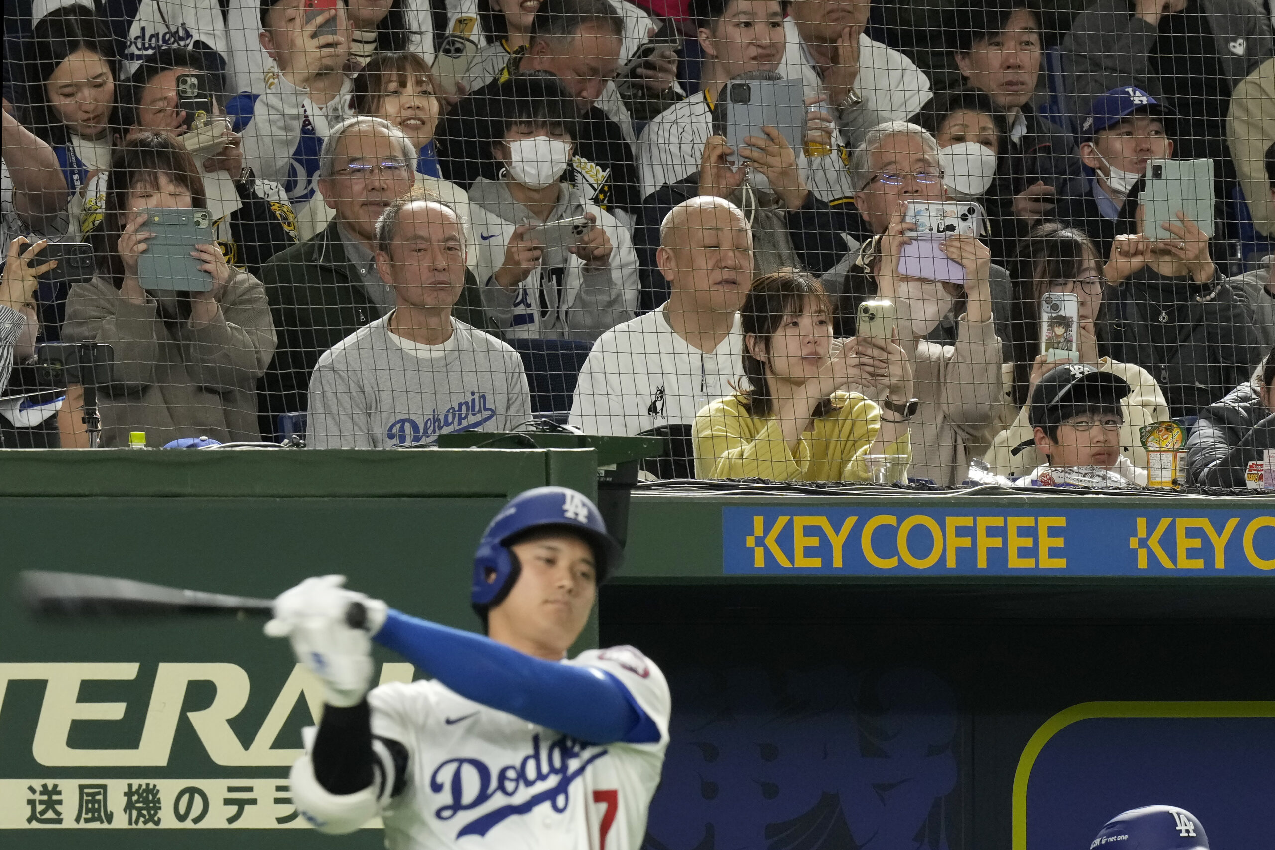 Dodgers star Shohei Ohtani, bottom, swings in the on-deck circle...