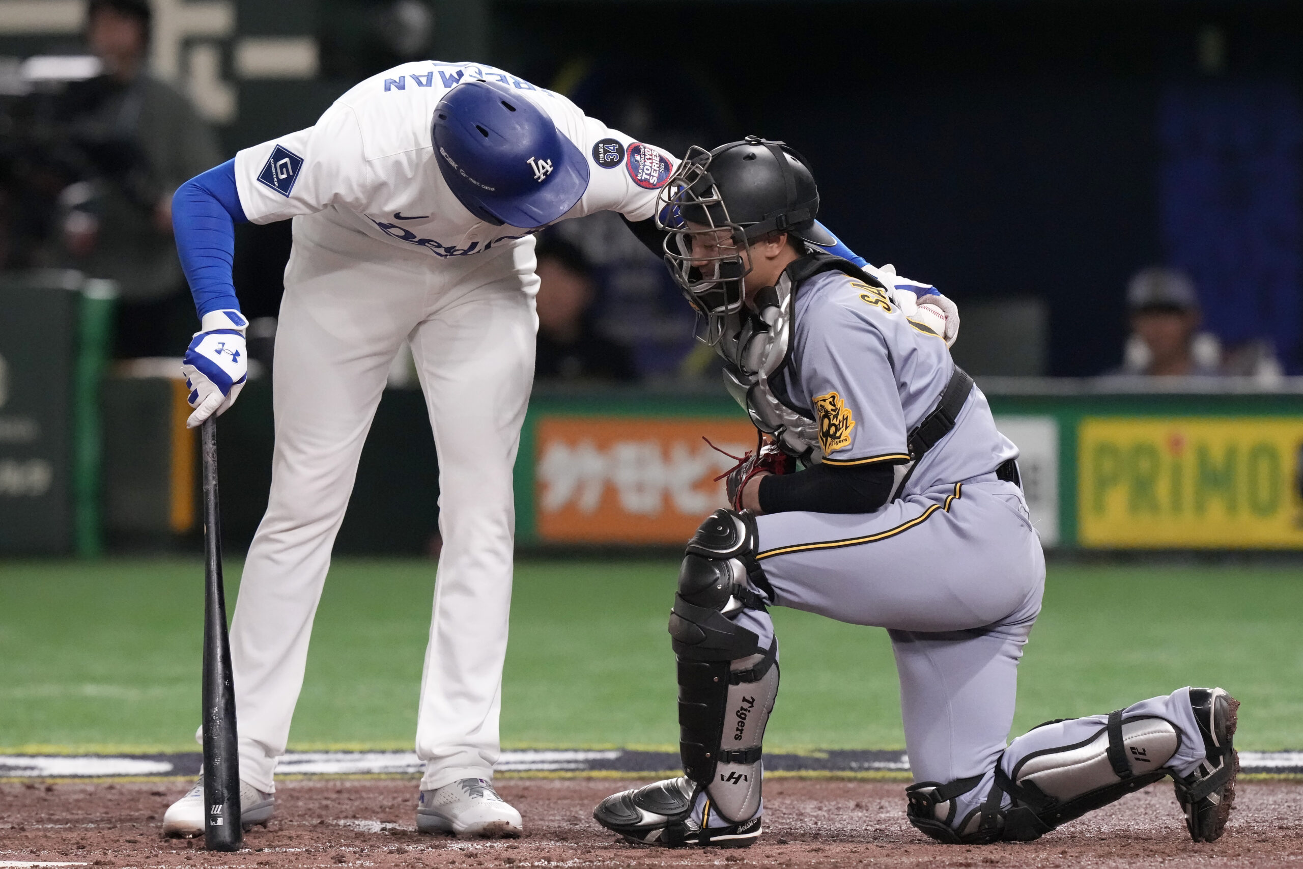 The Dodgers’ Freddie Freeman, left, checks on Hanshin Tigers catcher...