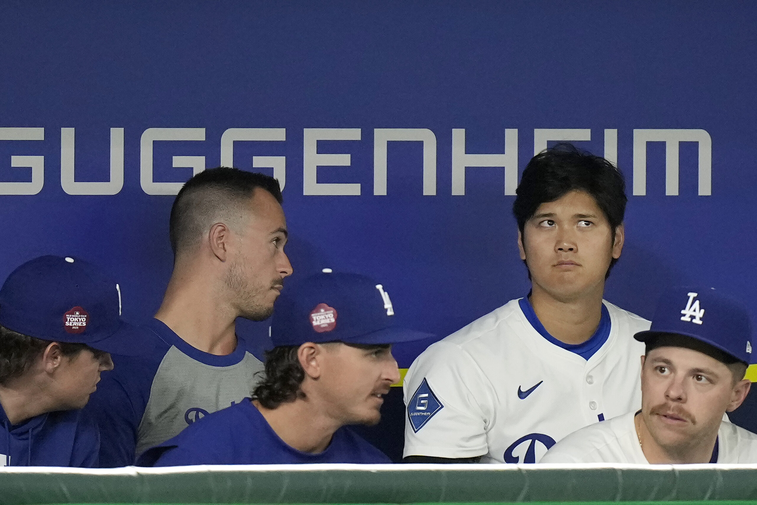 Dodgers star Shohei Ohtani, top right, sits in the dugout...