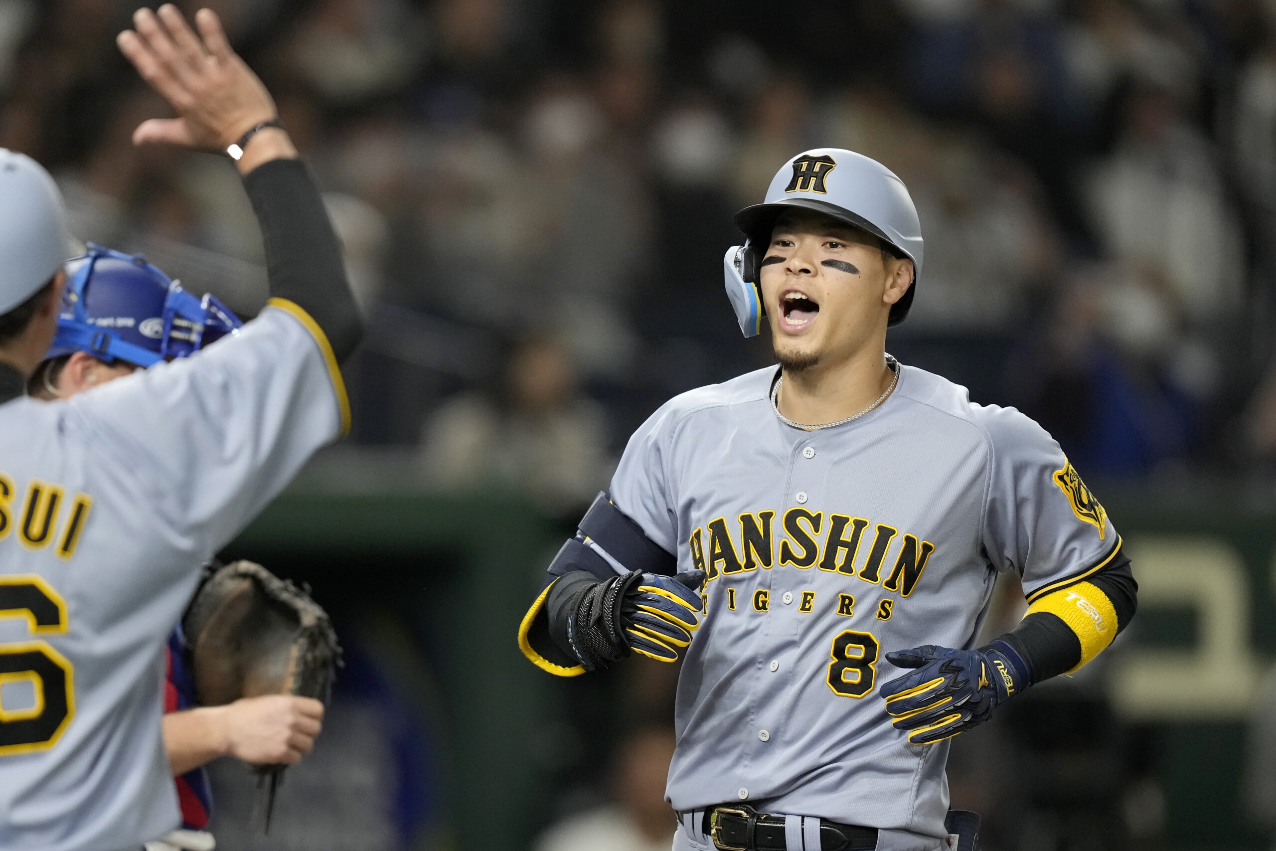 The Hanshin Tigers’ Teruaki Sato (8) celebrates after hitting a...