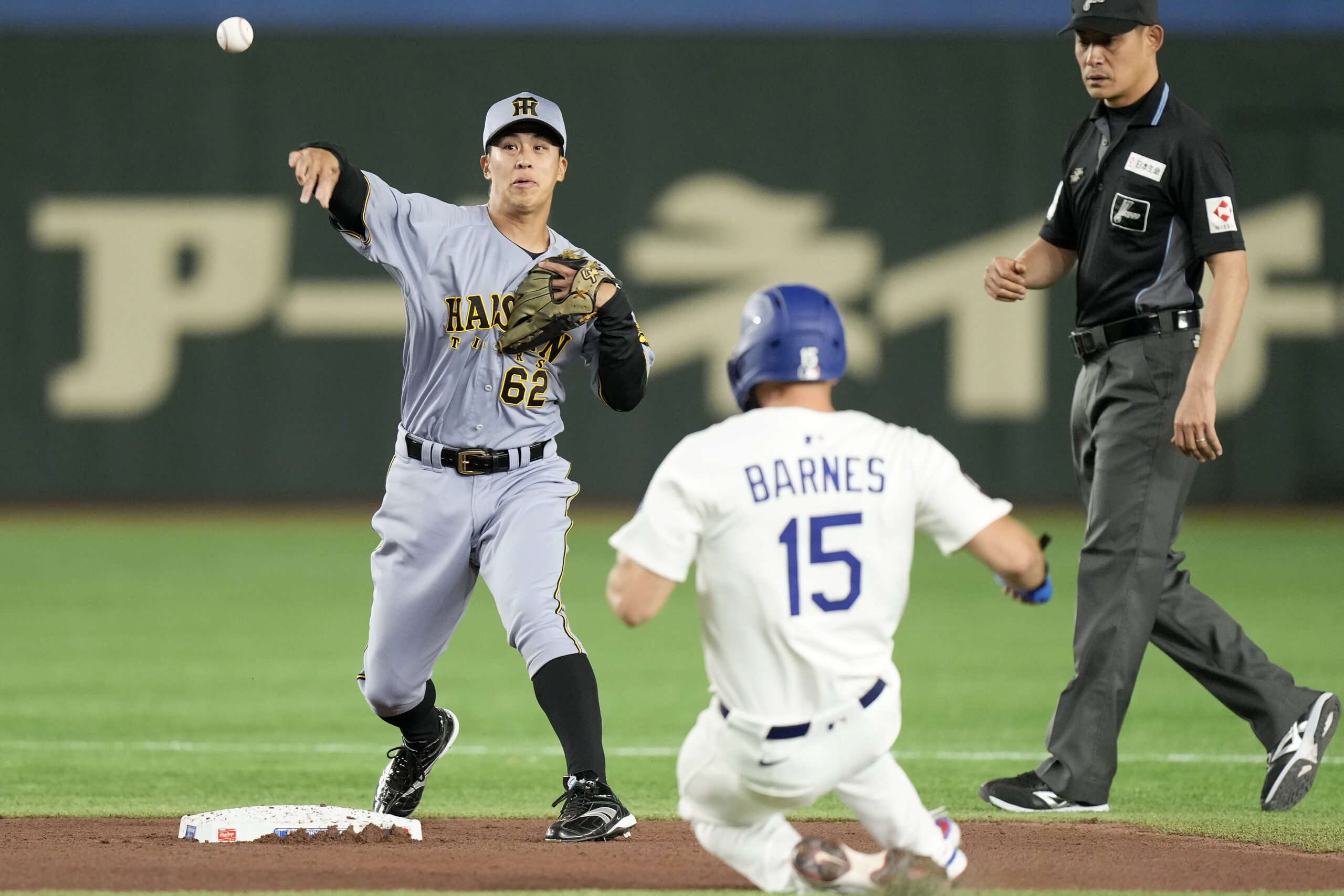 The Hanshin Tigers’ Kai Ueda (62) throws to first base...