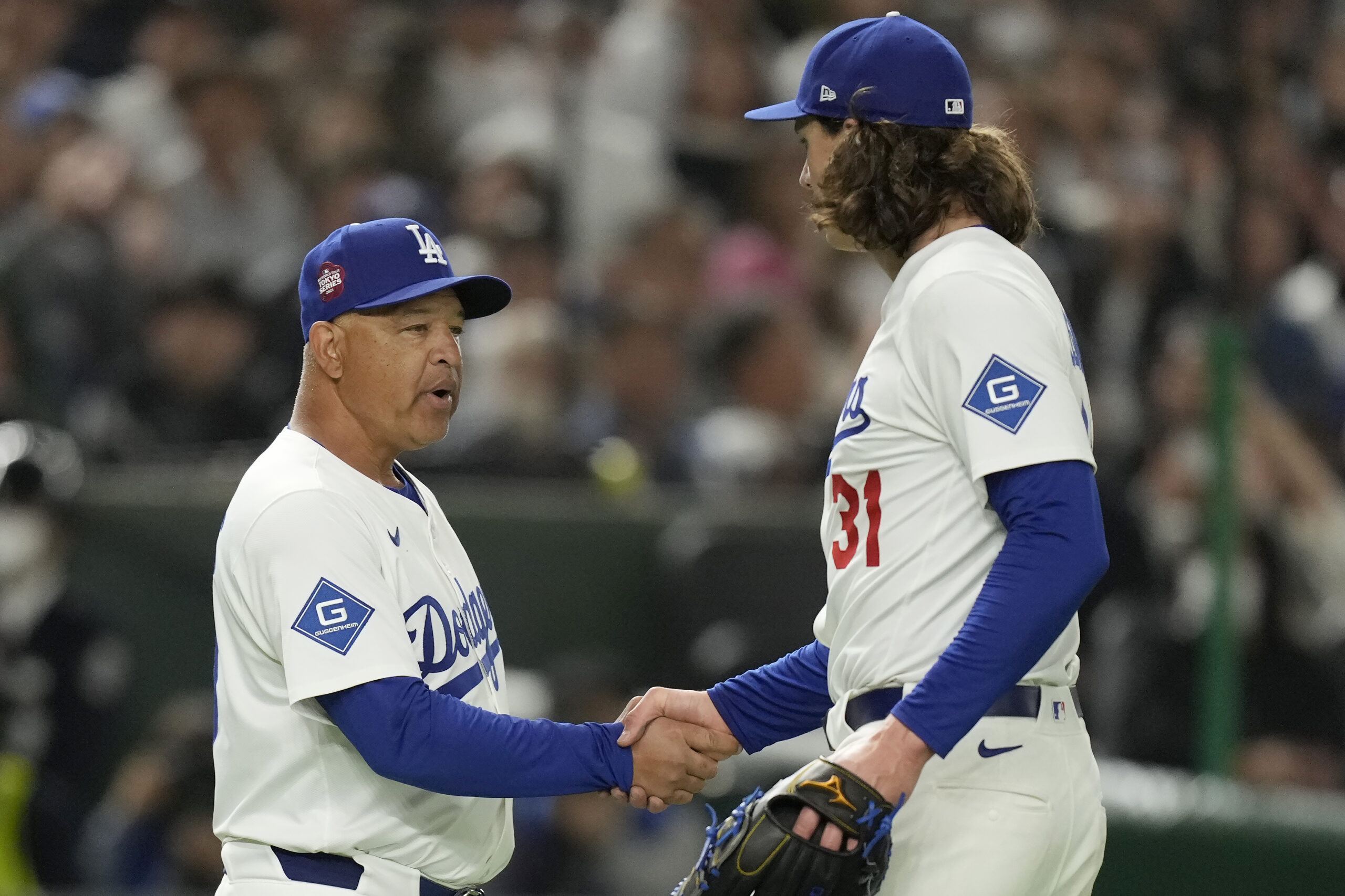 Dodgers manager Dave Roberts, left, shakes hands with pitcher Tyler...