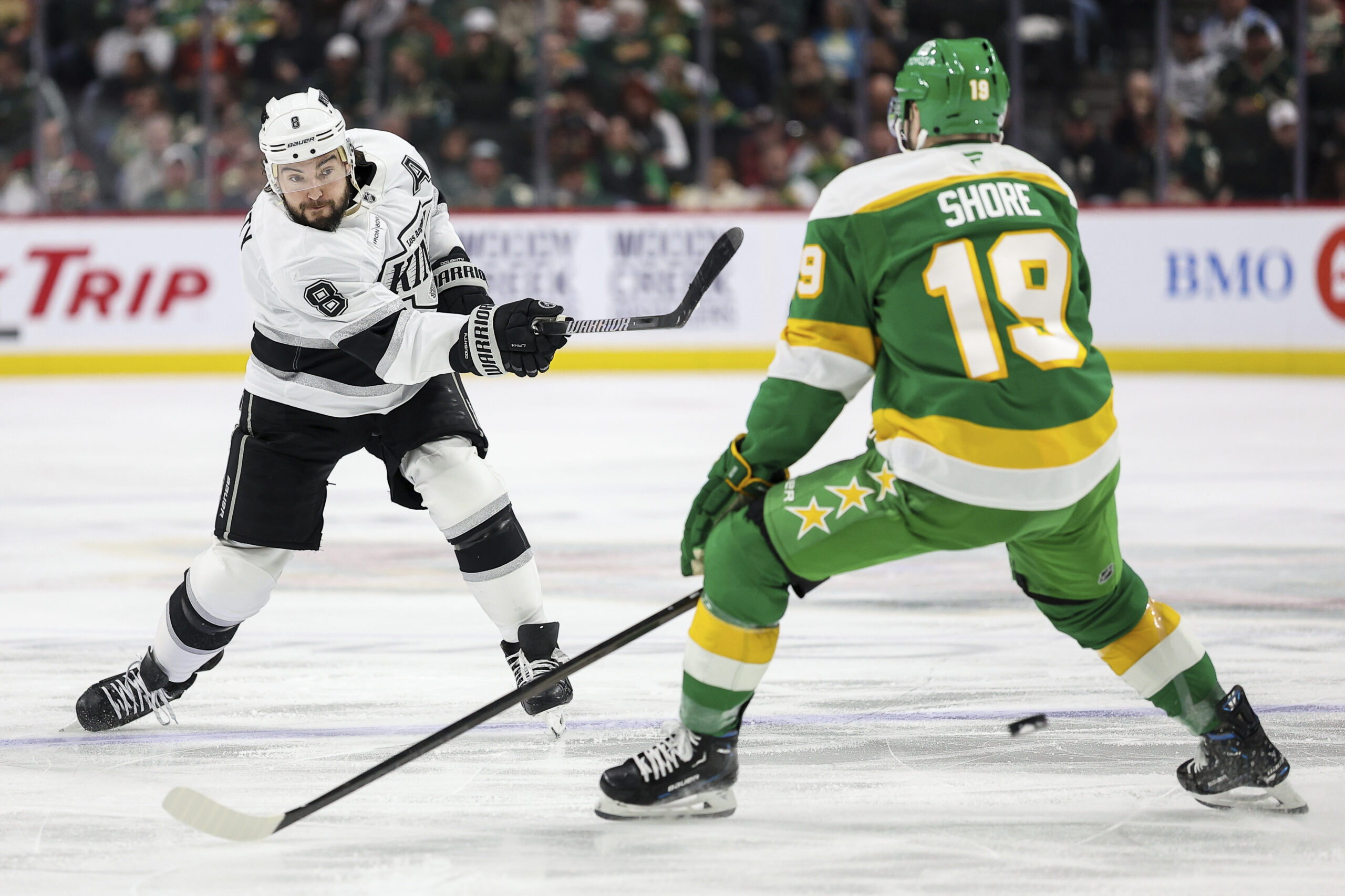 Kings defenseman Drew Doughty, left, shoots as Minnesota Wild center...