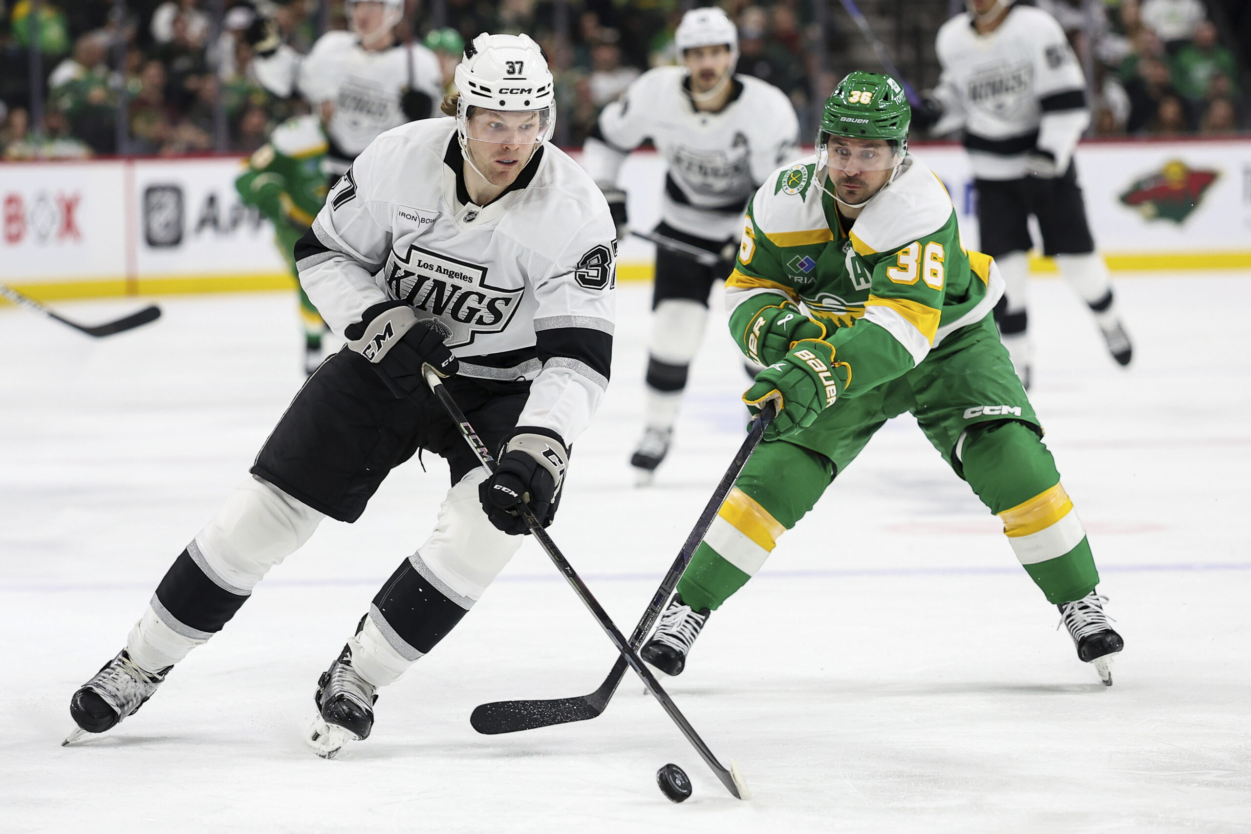 Kings left wing Warren Foegele, left, skates with the puck...