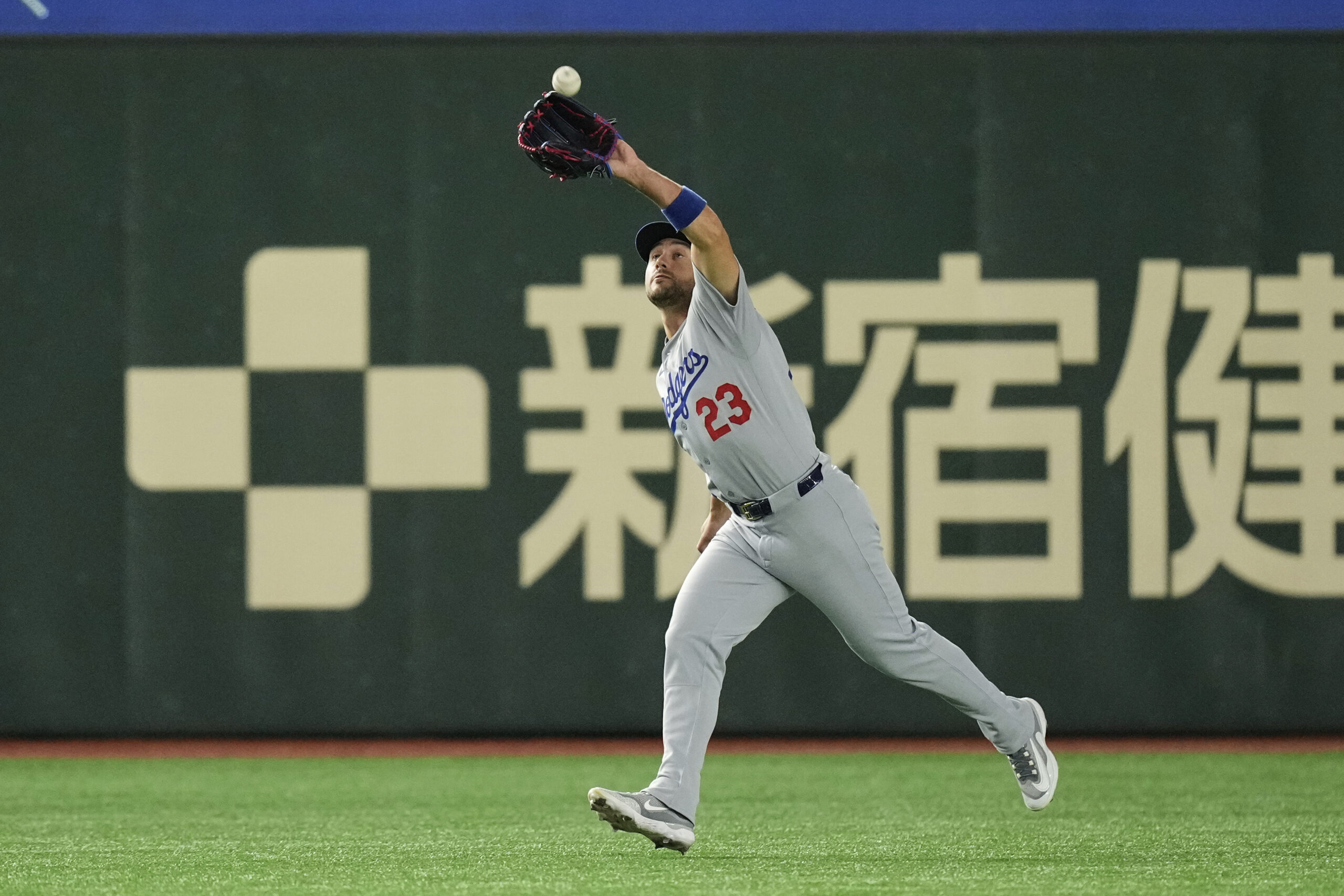 Los Angeles Dodgers left fielder Michael Conforto reaches up to...