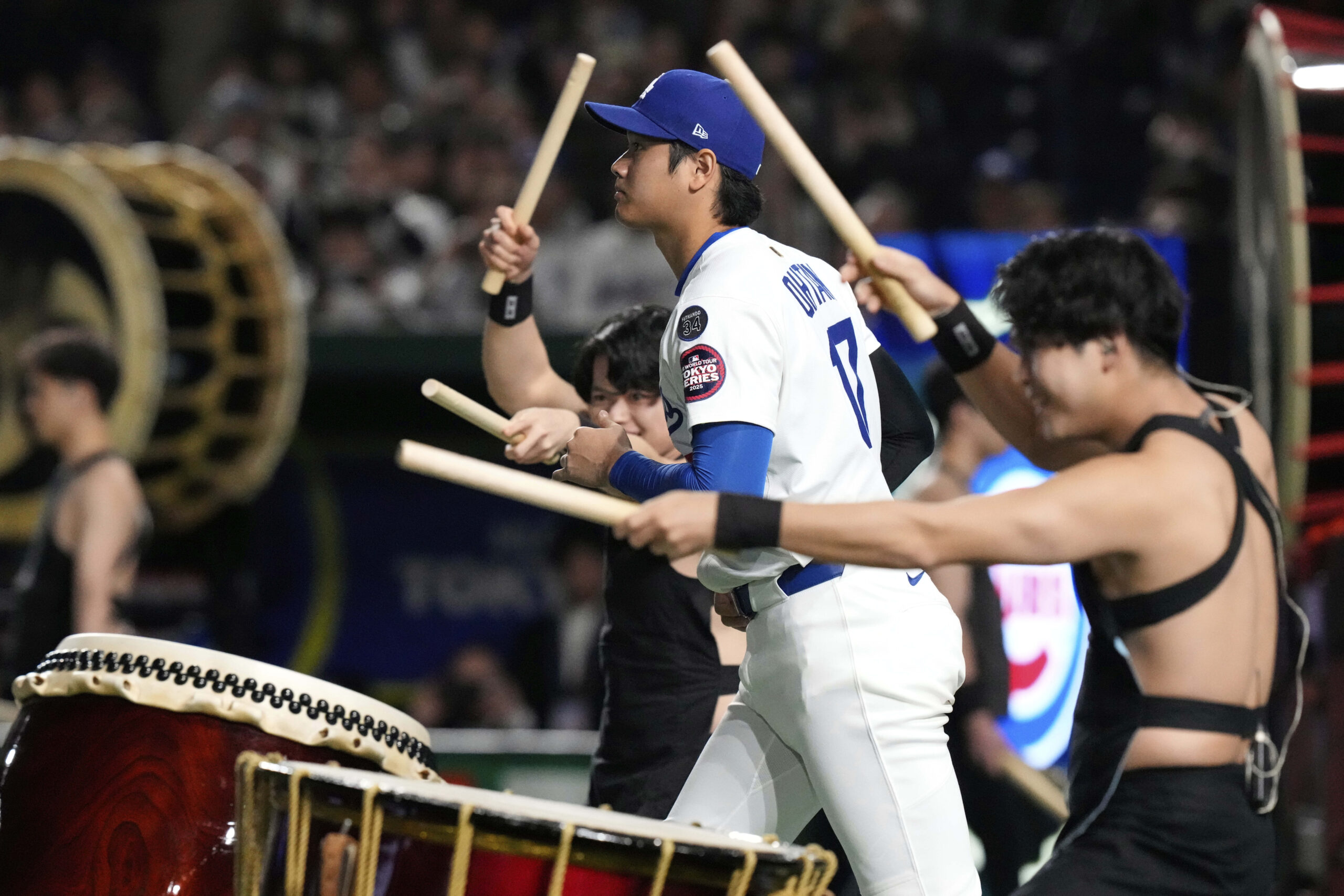 The Dodgers’ Shohei Ohtani jogs onto the field past entertainers...