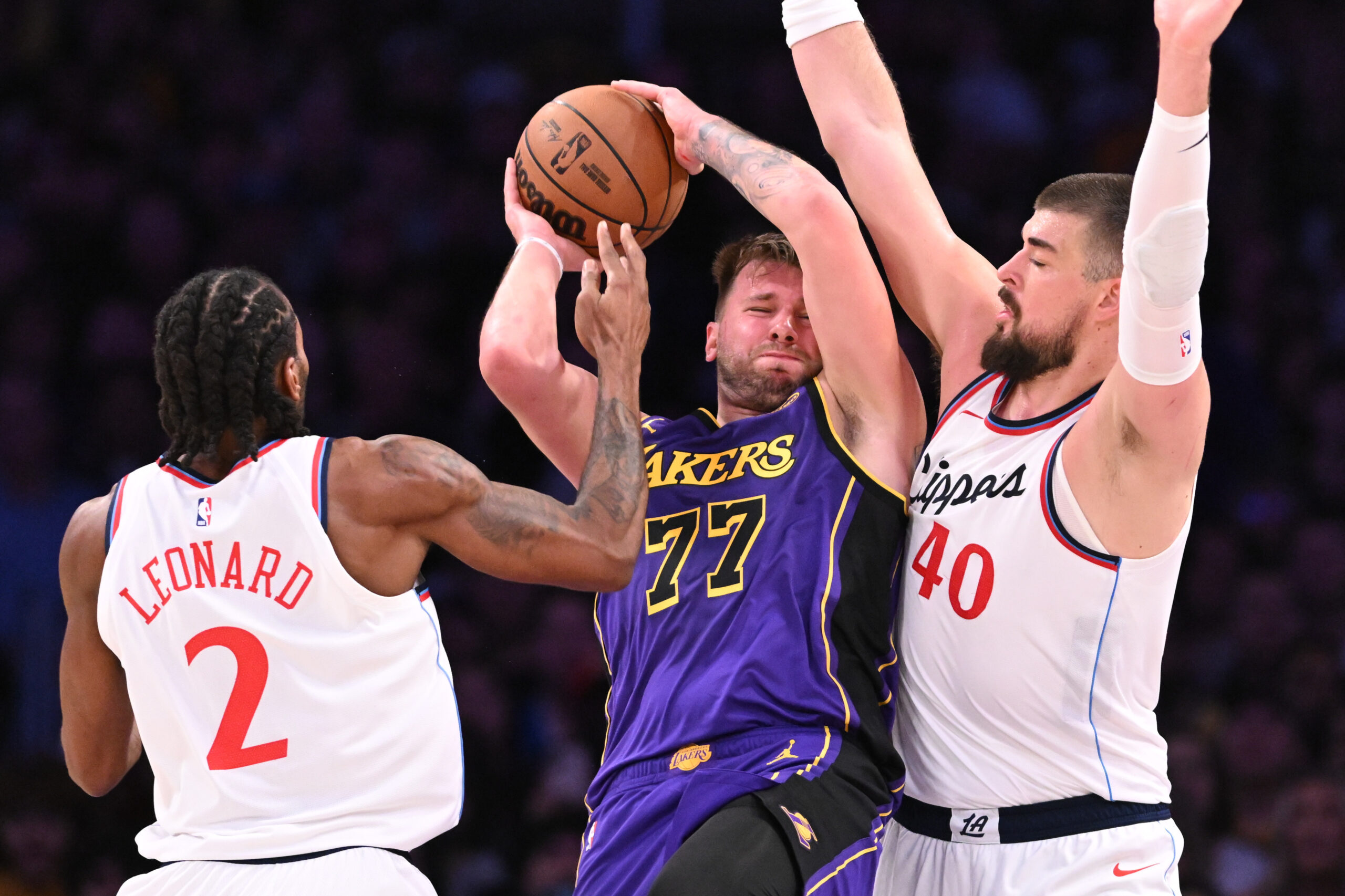 Lakers star Luka Doncic grabs a rebound between Clippers star...