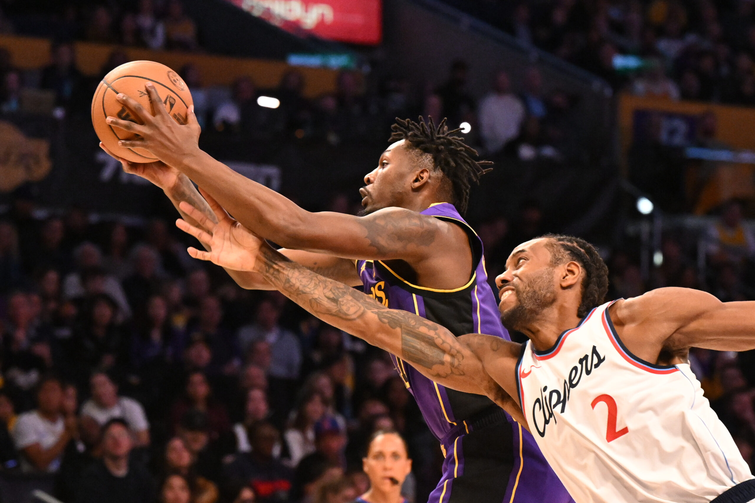 Lakers forward Dorian Finney-Smith, left, grabs a rebound over Clippers...