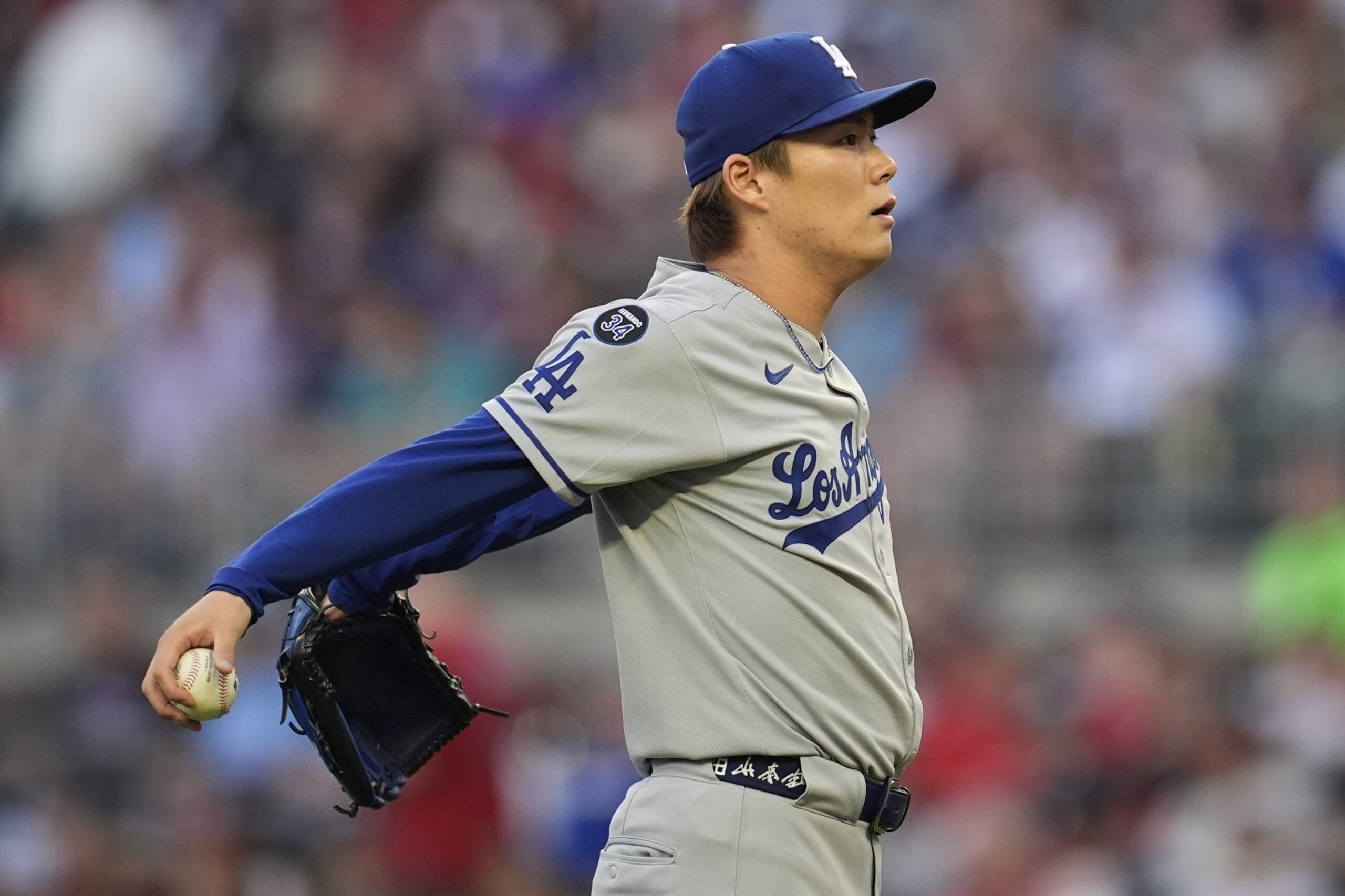 Dodgers starting pitcher Yoshinobu Yamamoto reacts after catching a ball...