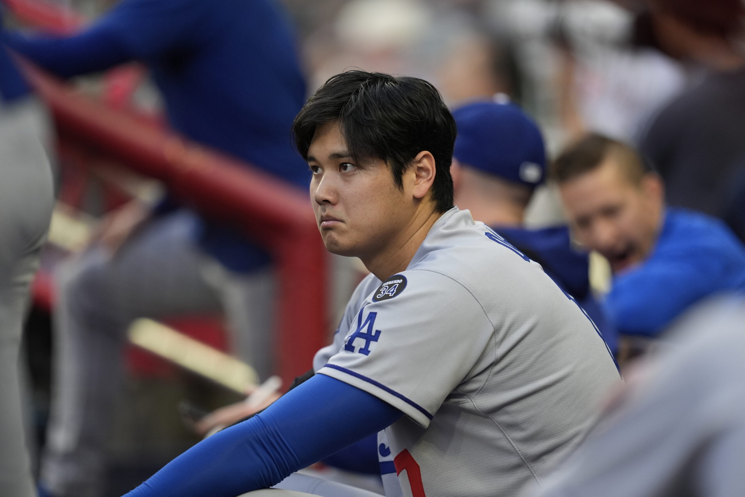 Dodgers star Shohei Ohtani sits in the dugout in the...