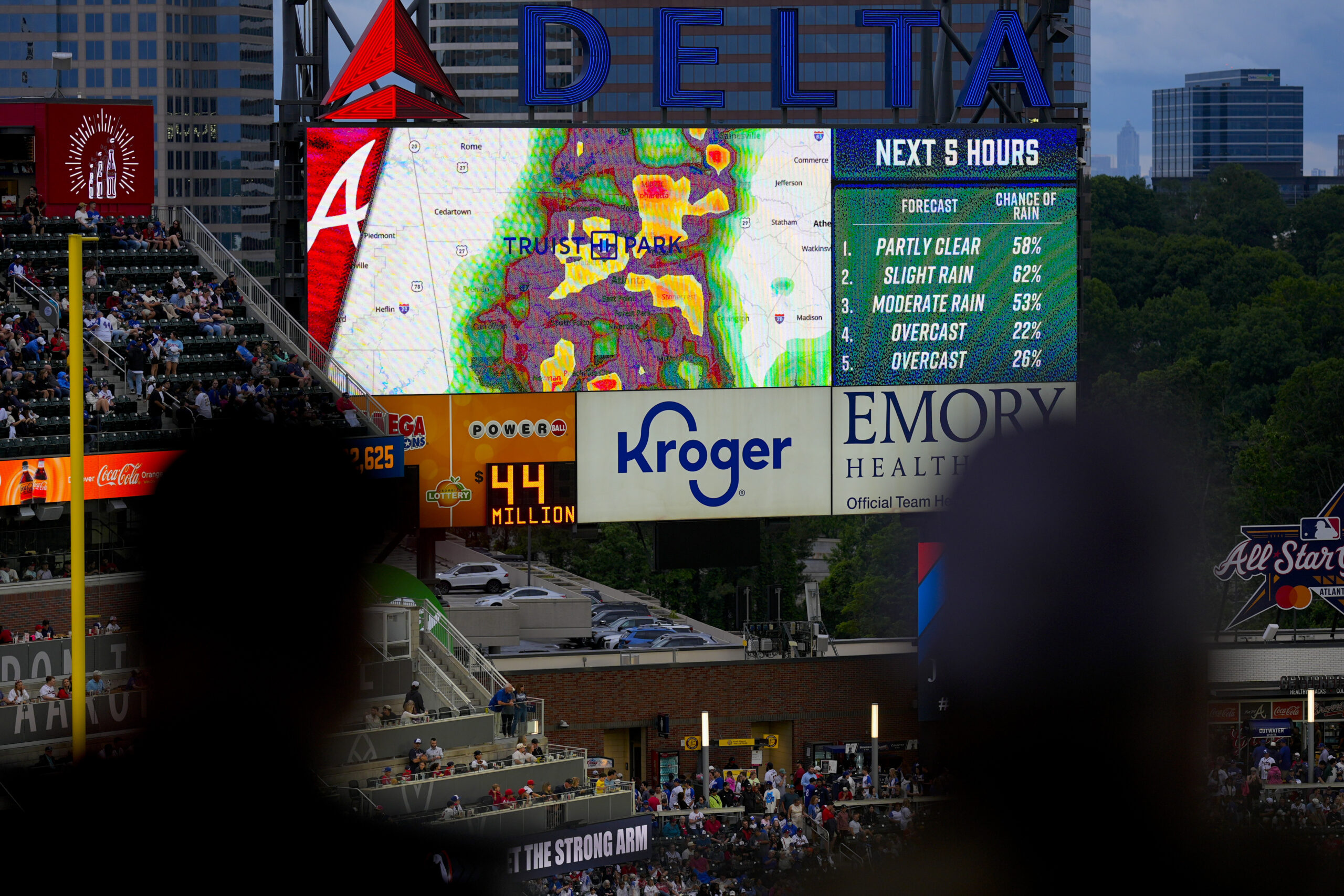 Fans watch the radar displayed before a rain-delayed baseball game...