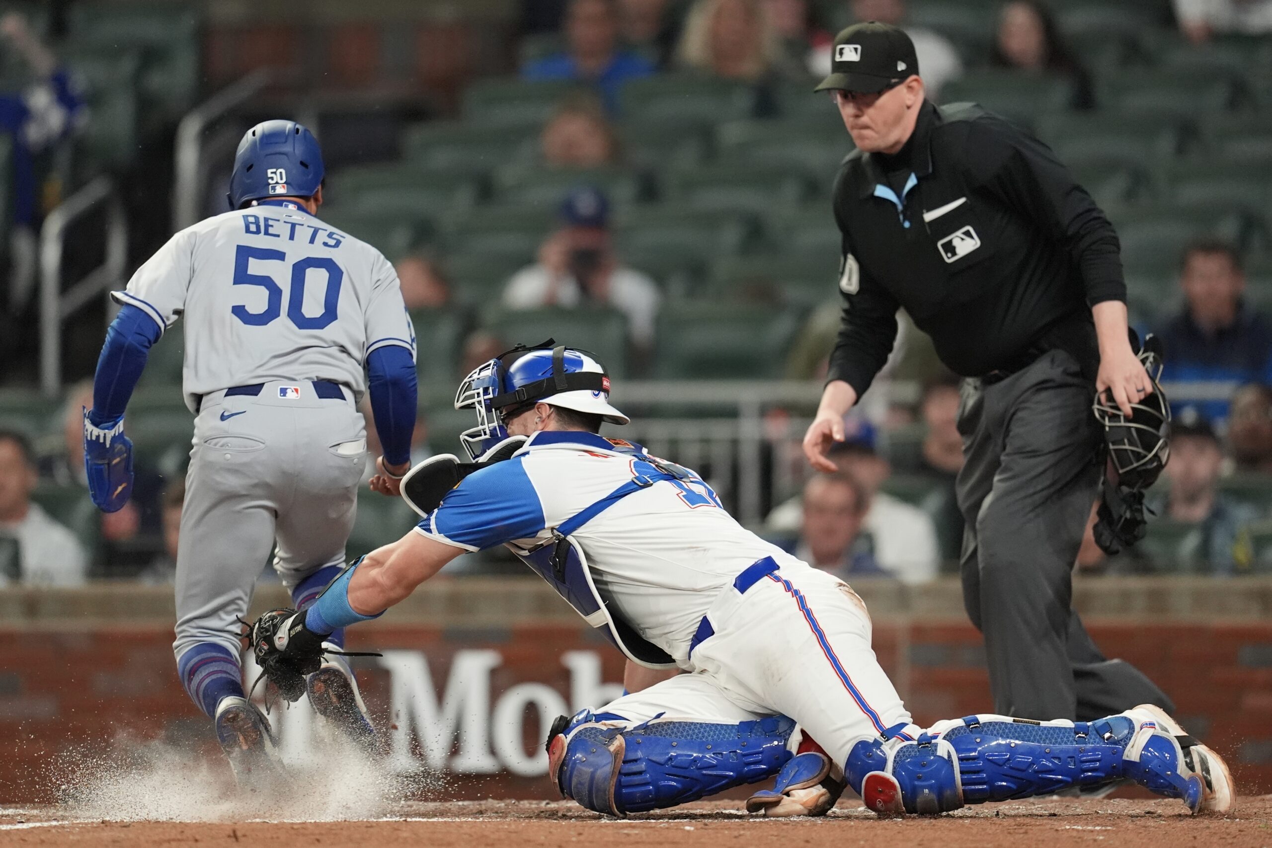 The Dodgers’ Mookie Betts, left, scores before a late tag...