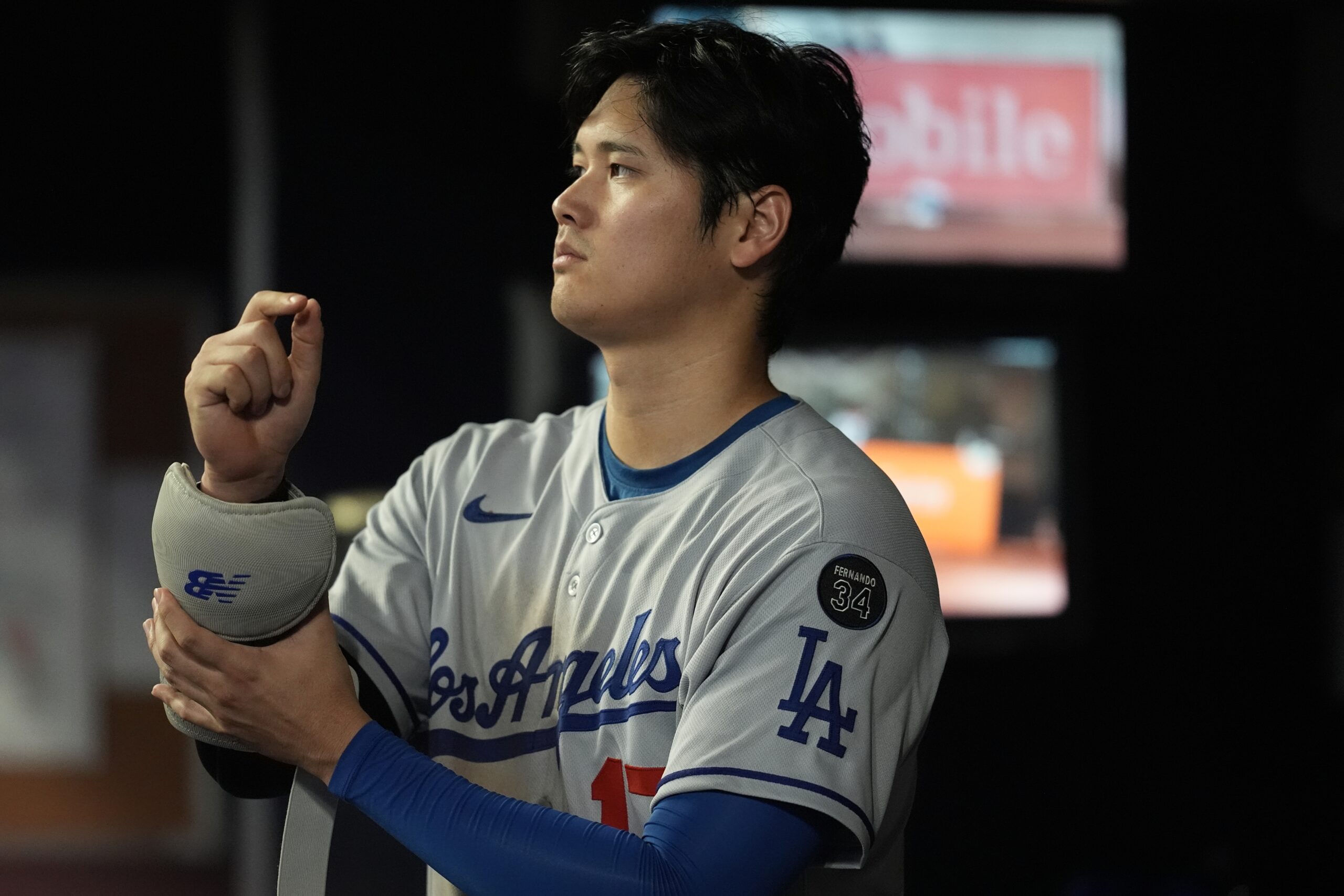 Dodgers star Shohei Ohtani stands in the dugout in the...