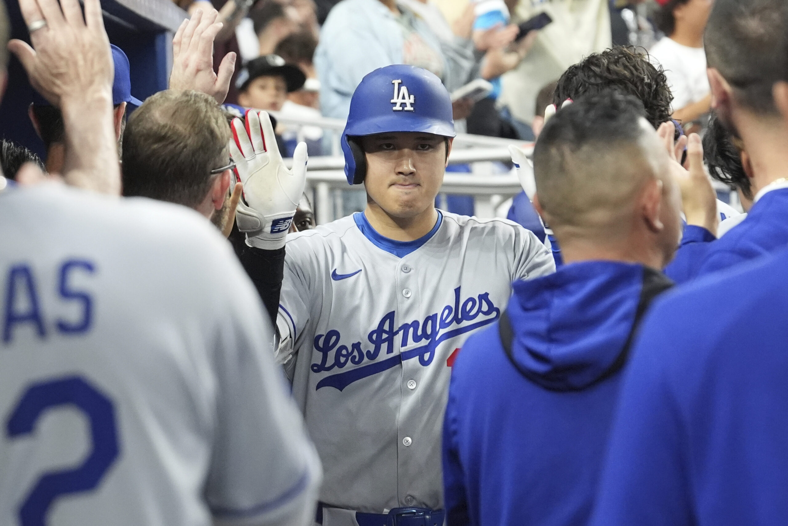 Dodgers star Shohei Ohtani celebrates in the dugout after hitting...