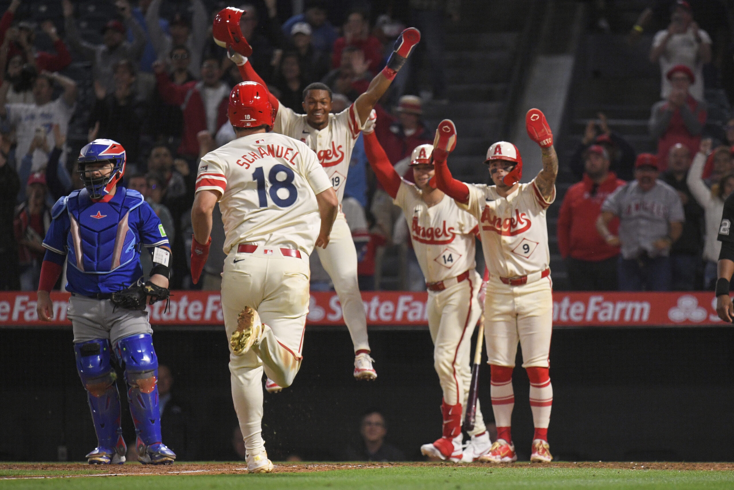 The Angels’ Nolan Schanuel, second from left, runs home to...