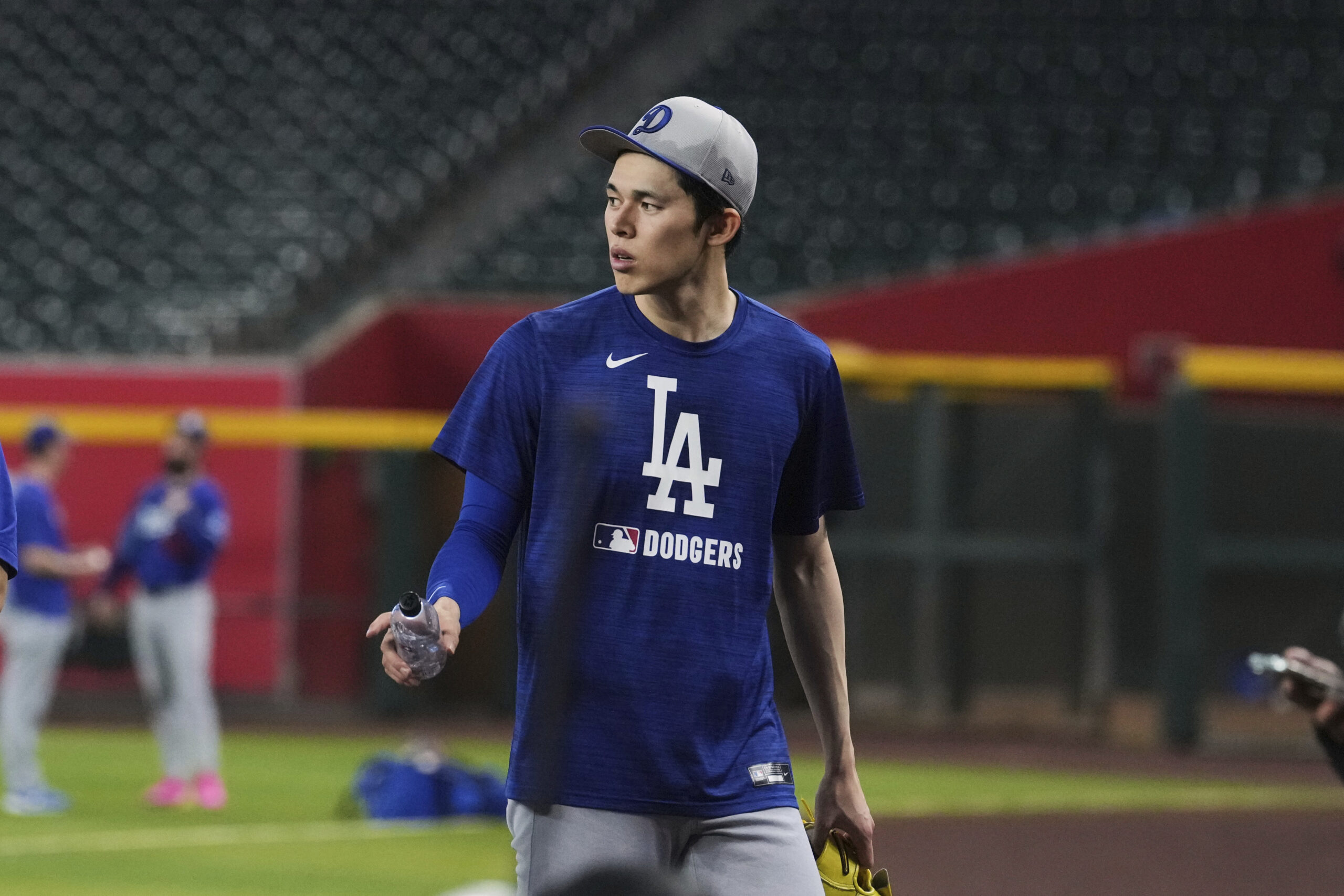 Dodgers pitcher Roki Sasaki walks off the field after warming...