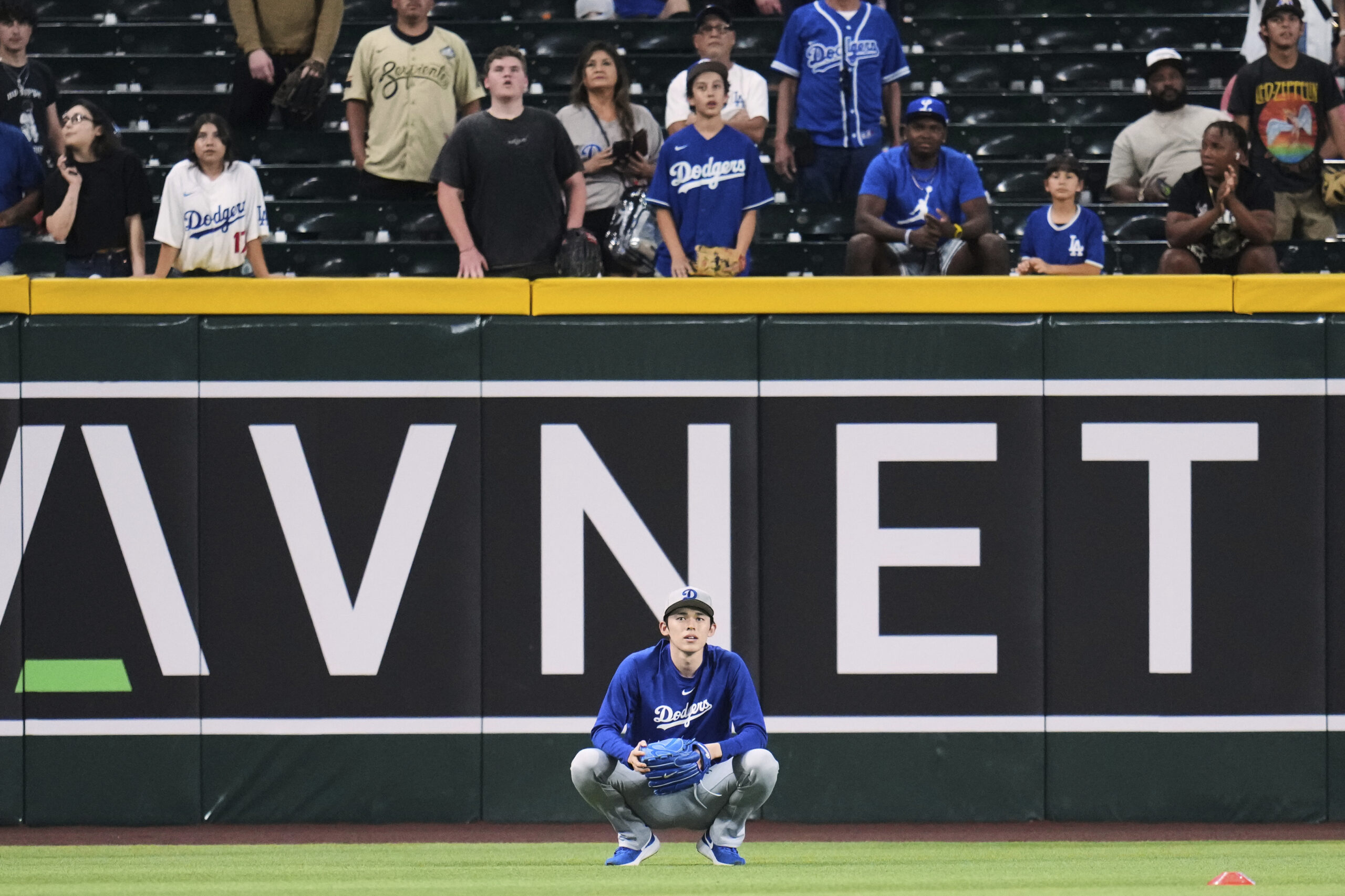 Dodgers pitcher Roki Sasaki watches from the outfield as teammates...