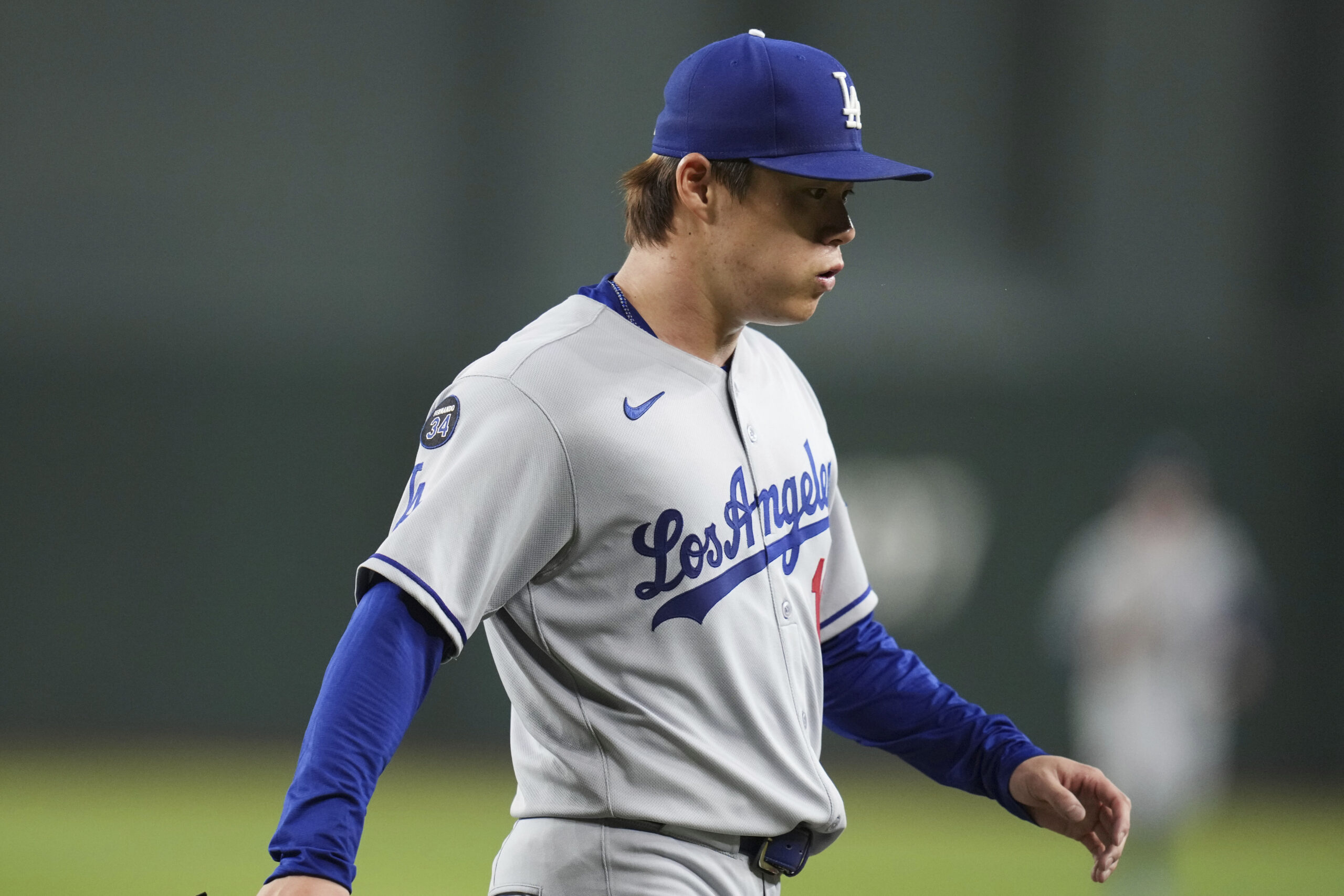 Dodgers starting pitcher Yoshinobu Yamamoto exhales as he walks back...