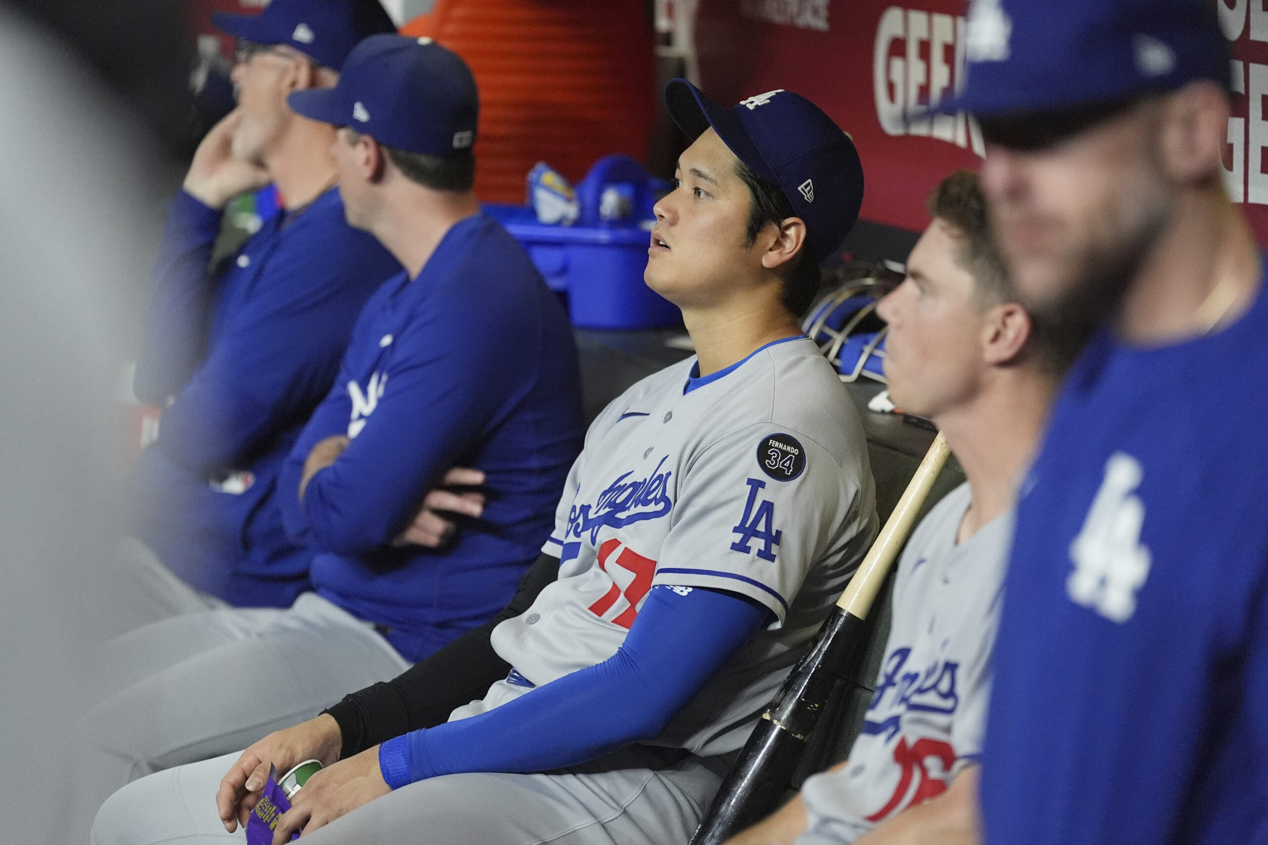 Dodgers star Shohei Ohtani sits with teammates in the dugout...